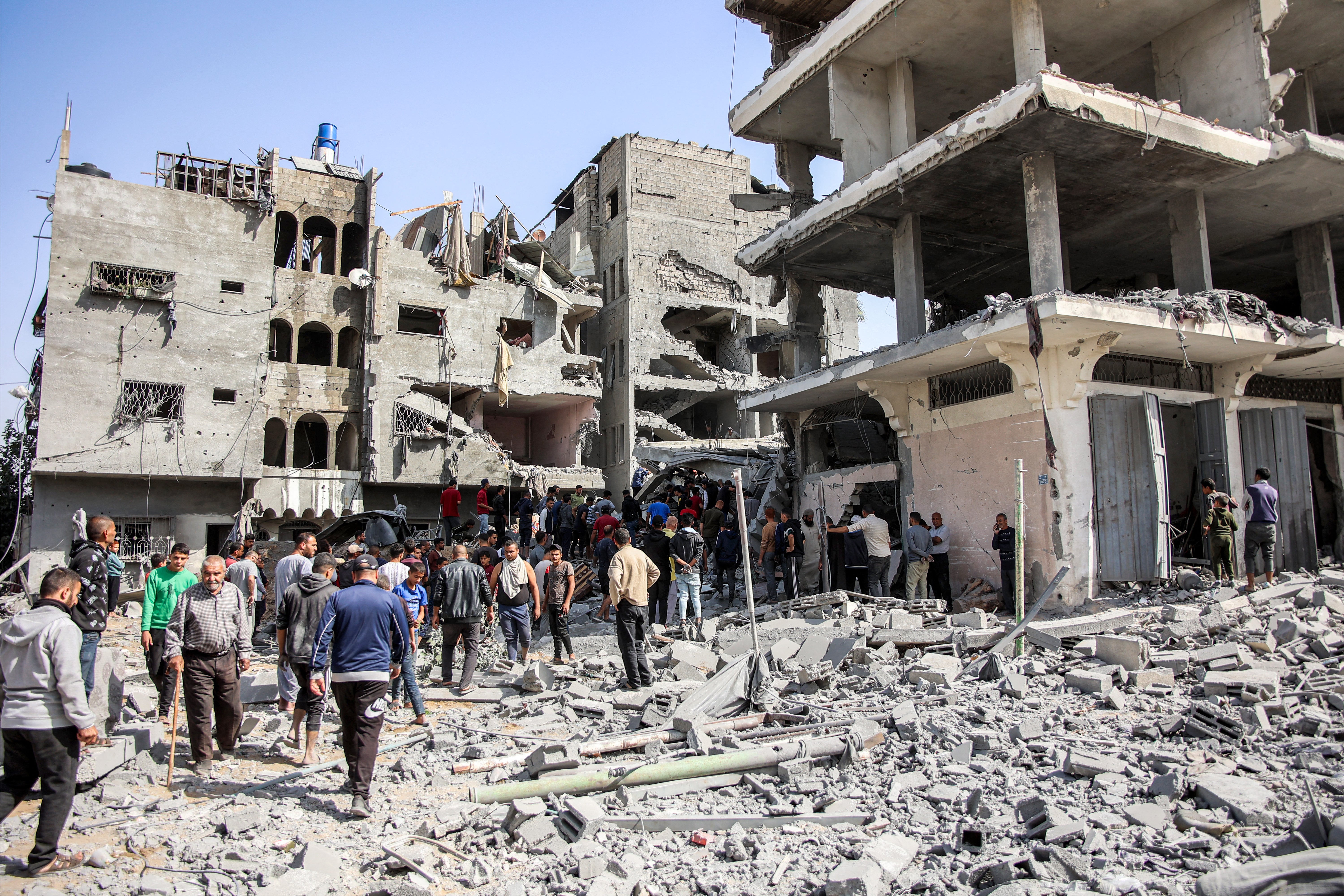 People gather to search for survivors and victims through the rubble following Israeli bombardment on the four-storey Muqat family house in northern Gaza on 26 October 2024