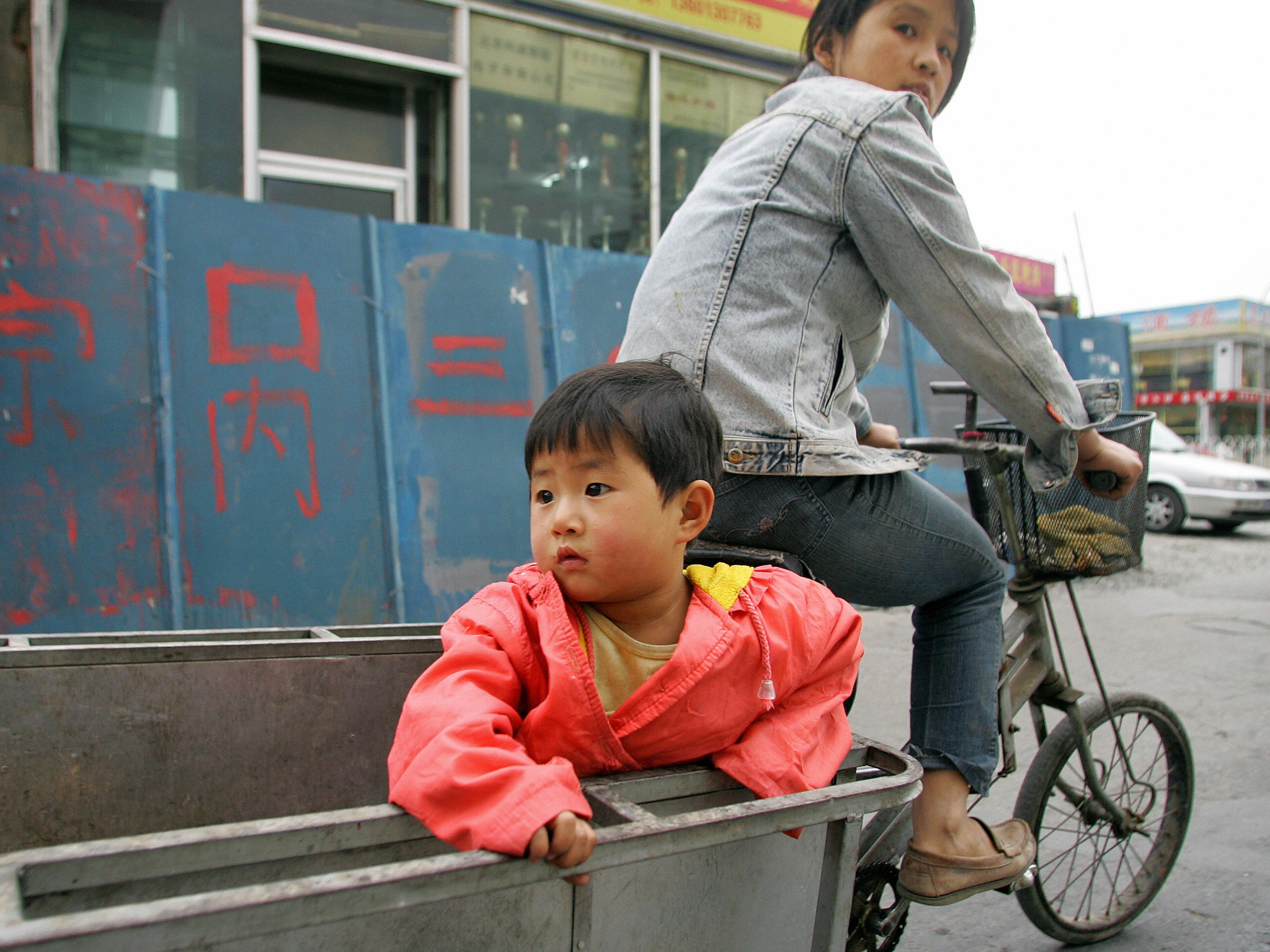 File: A child holds on while riding on the back of a tricycle, 8 May 2007 in Beijing