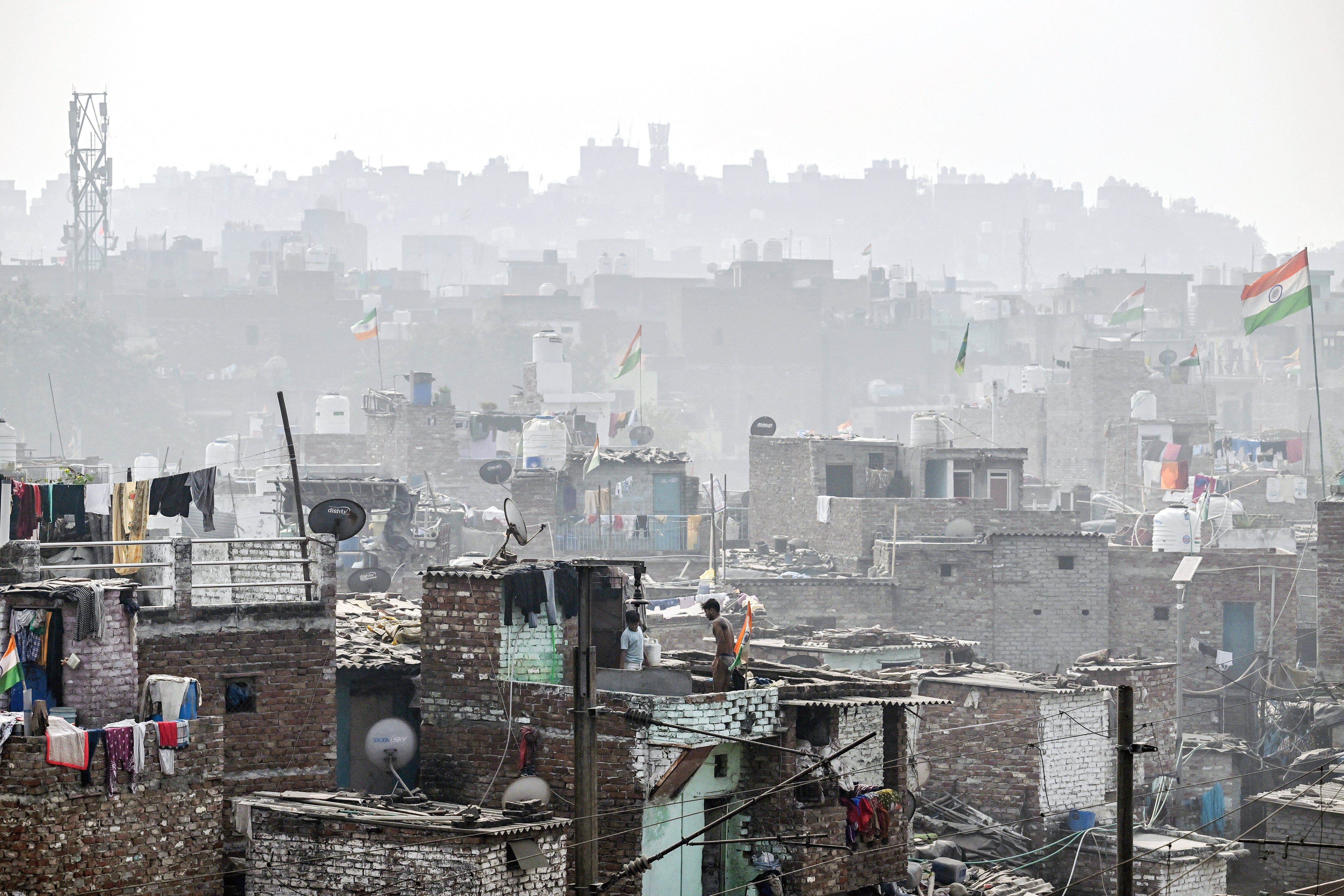 Men gather on the terrace of a house in a residential area engulfed in thick smog in Delhi