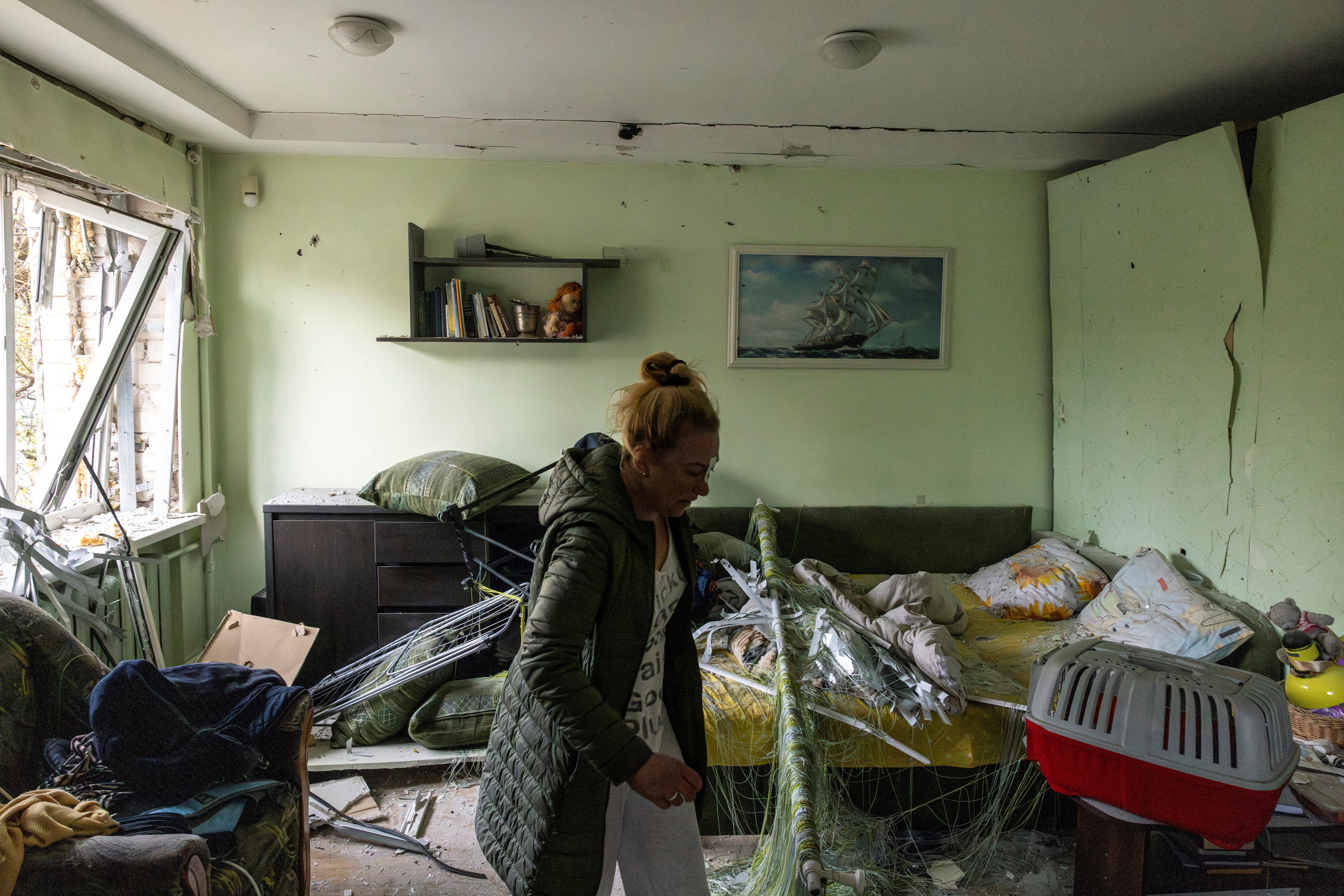 Vita Tkachenko, who was injured by flying debris while asleep, inspects the damage to her apartment after a Russian drone hit it