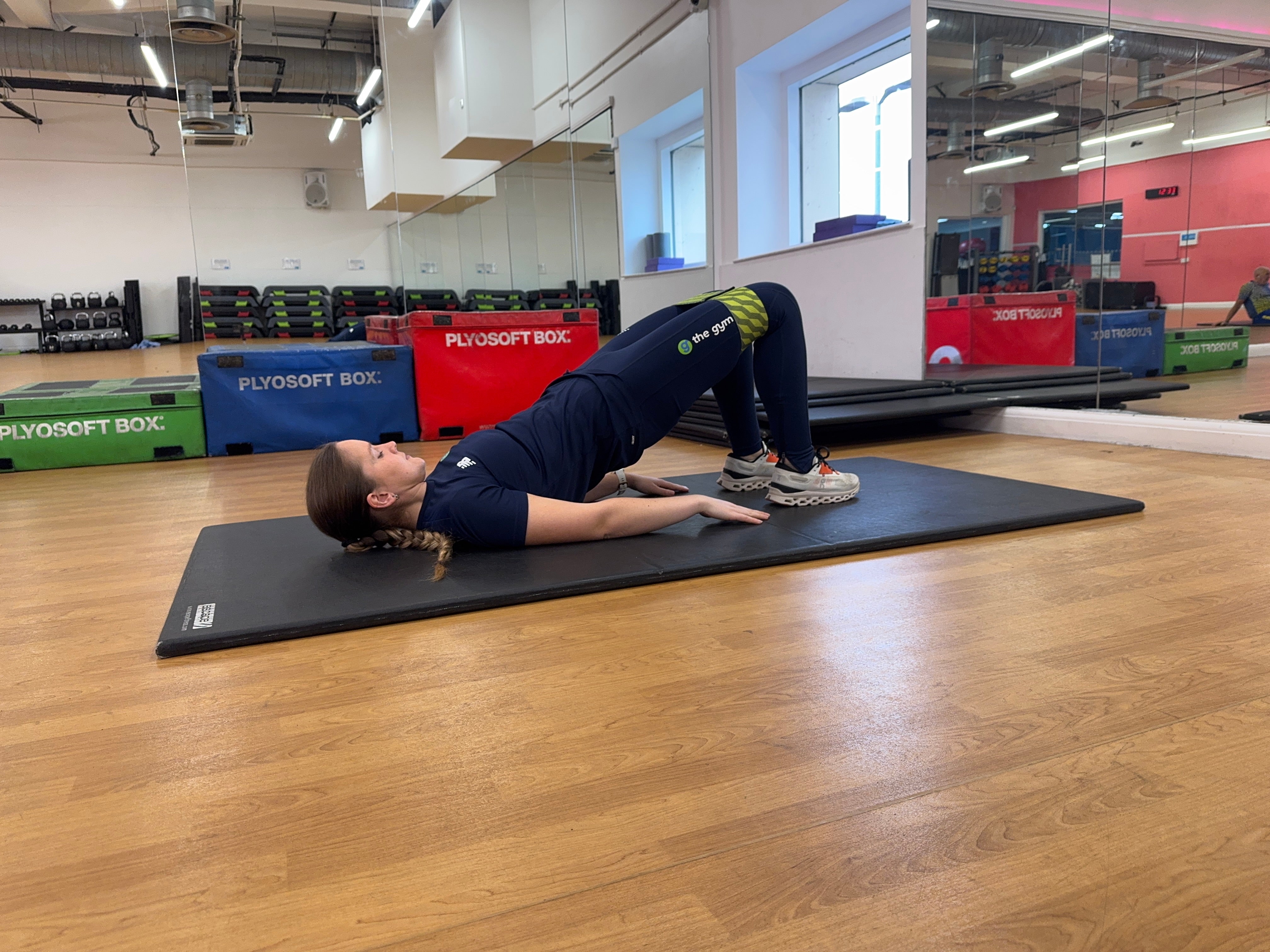 Trainer Sasha Bridgen demonstrating a glute bridge with abduction