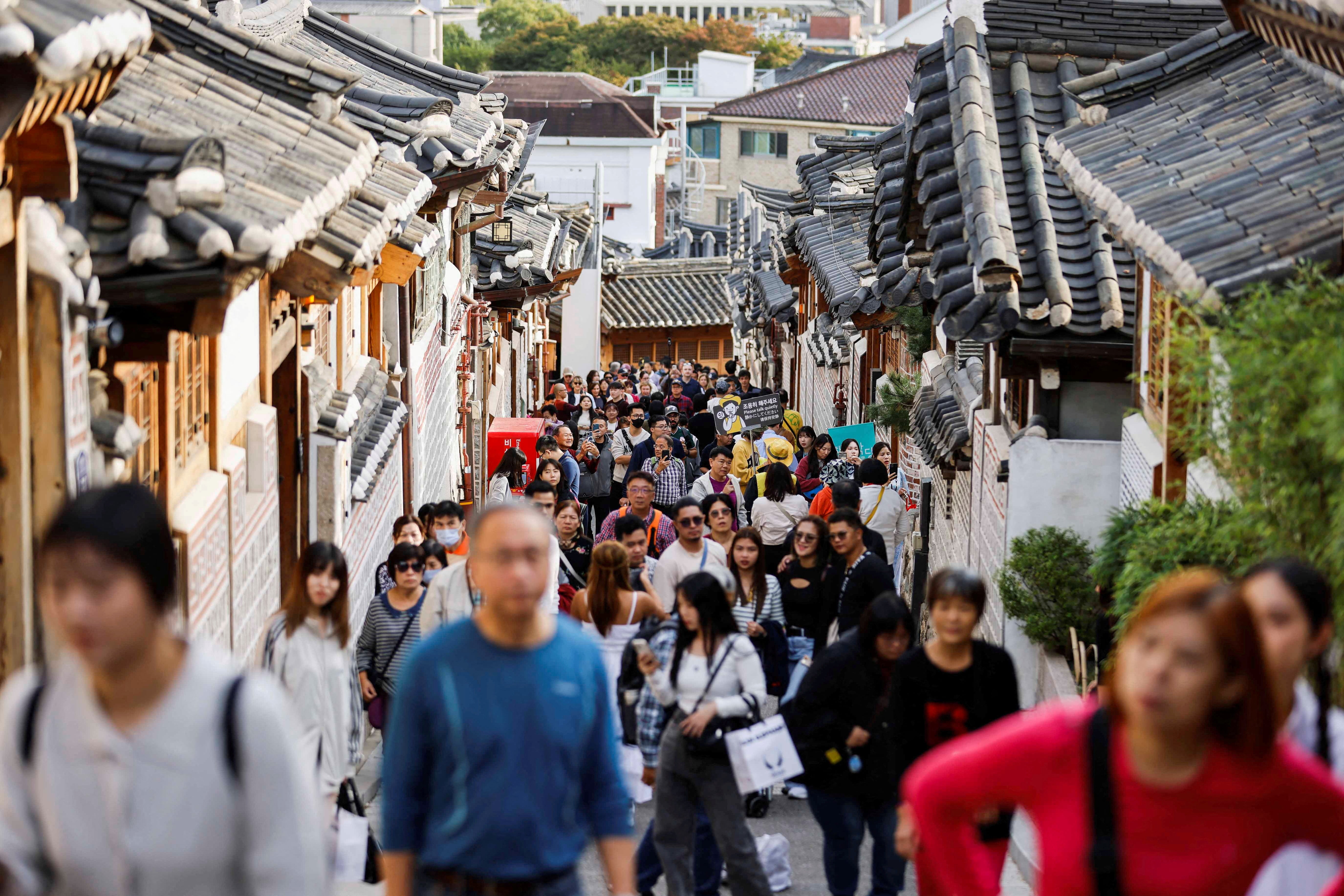 A large crowd of tourists walks through Bukchon Hanok Village in Seoul