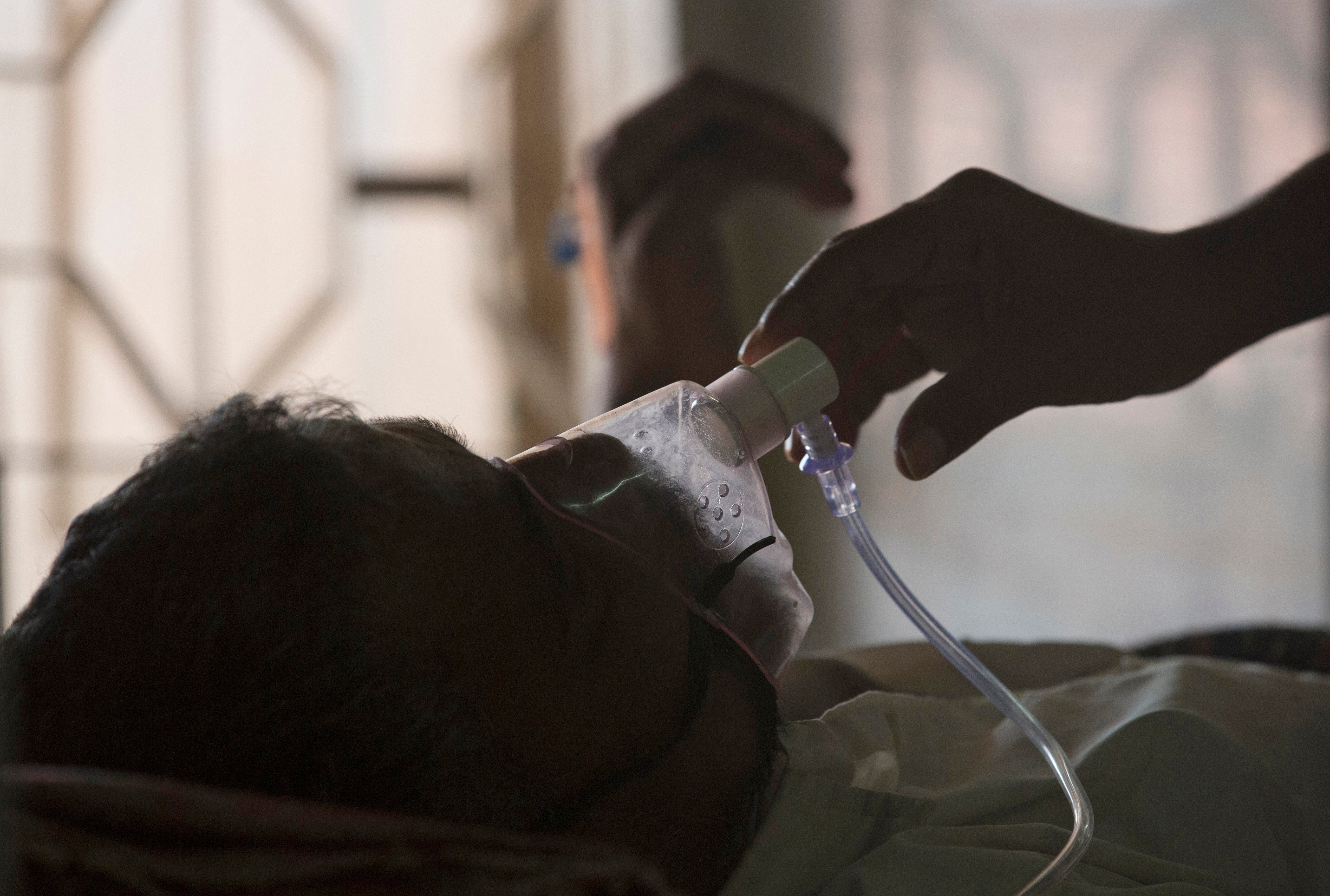 A relative adjusts the oxygen mask of a tuberculosis patient at a TB hospital on World Tuberculosis Day in Hyderabad, India