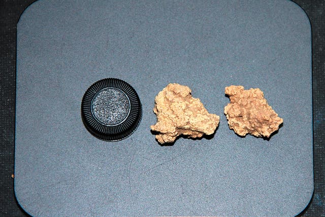 <p>An undated photo compares the size of a glass tube cap and two Bronze Age kefir cheese samples unearthed from a tomb site in the Xinjiang Uygur autonomous region</p>