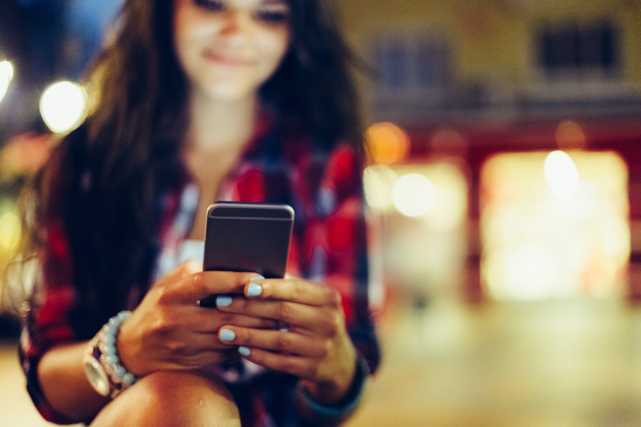 A teenage girl uses her cell phone. Social media use, emails, and texts all have a quantifiable carbon footprint that may surprise some users.