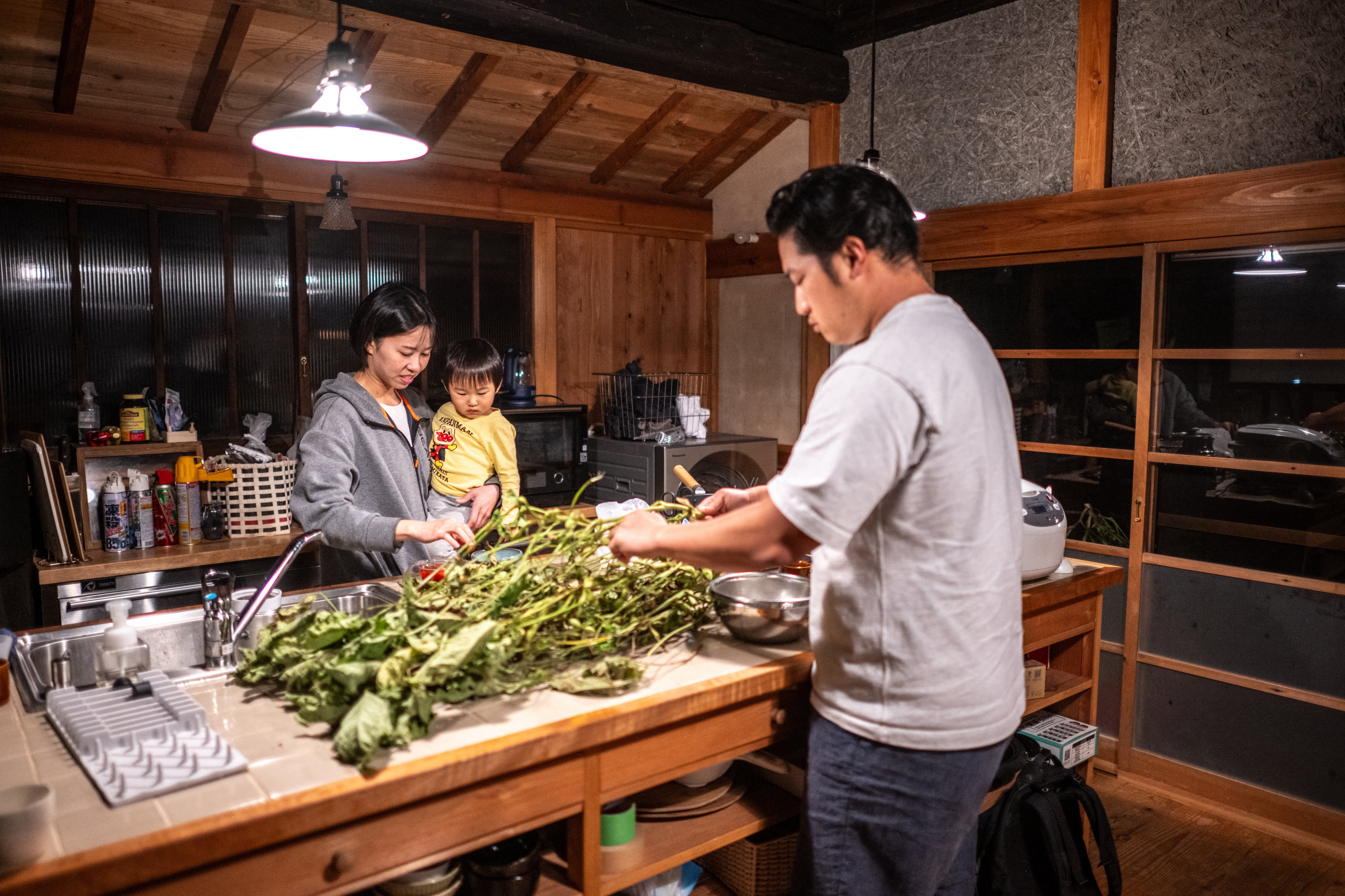 Rie Kato (left) and Toshiki Kato with their son Kuranosuke cooking dinner in their house