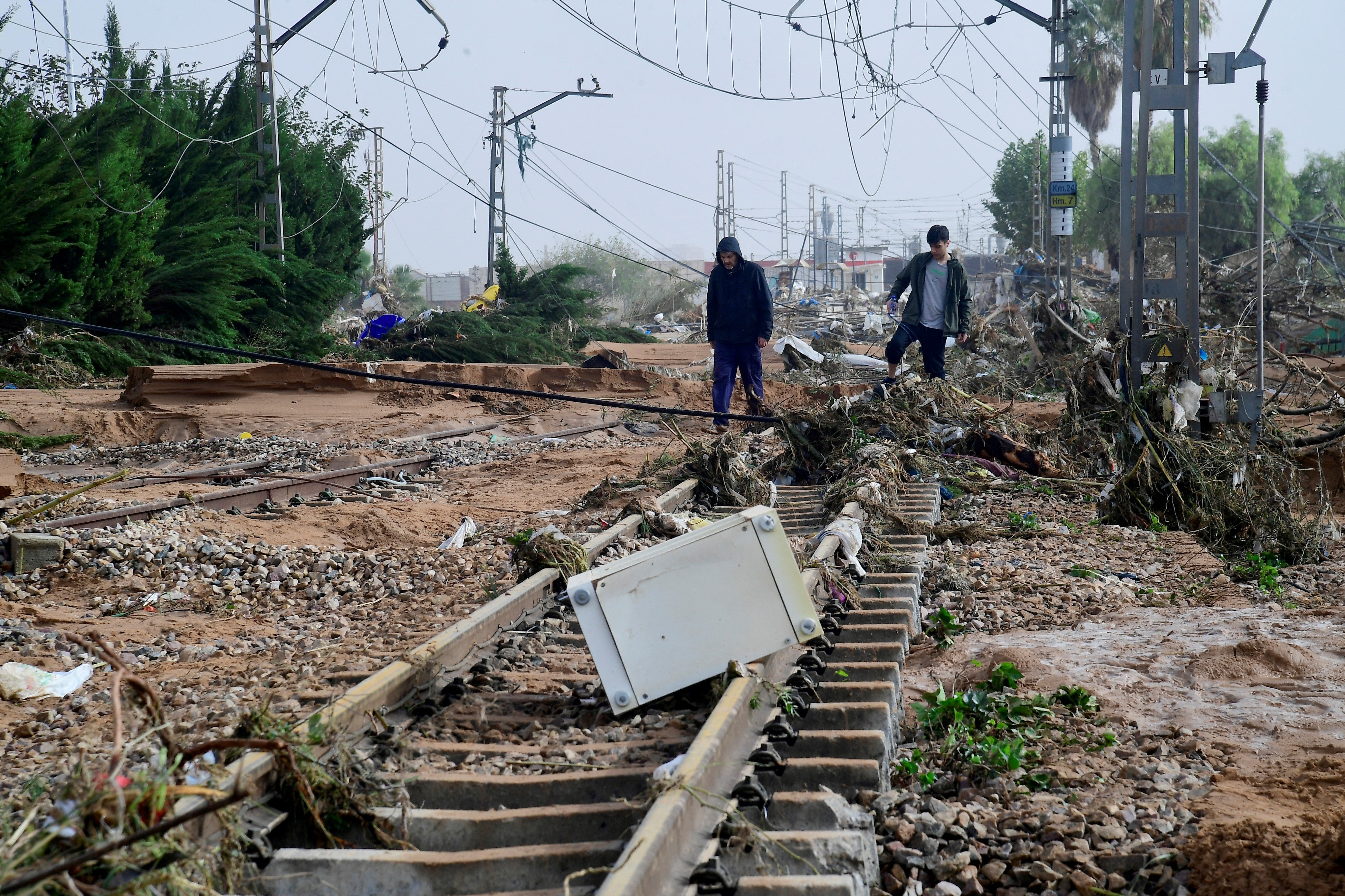 Residents walk among debris on a rail track following flood in Valencia