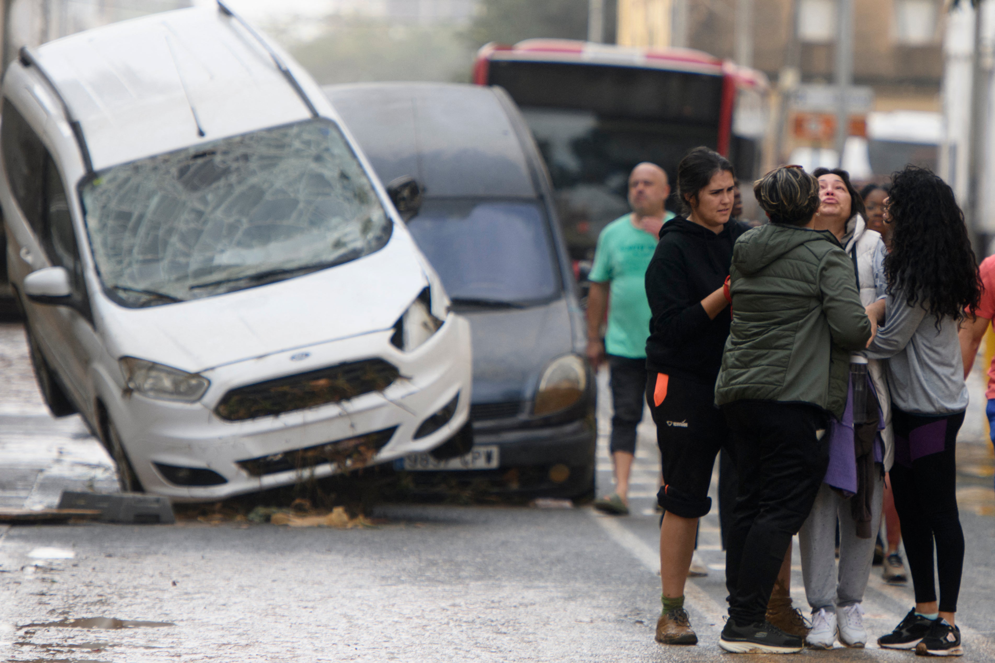 Residents talk in front of a pile-up of vehicles in the road