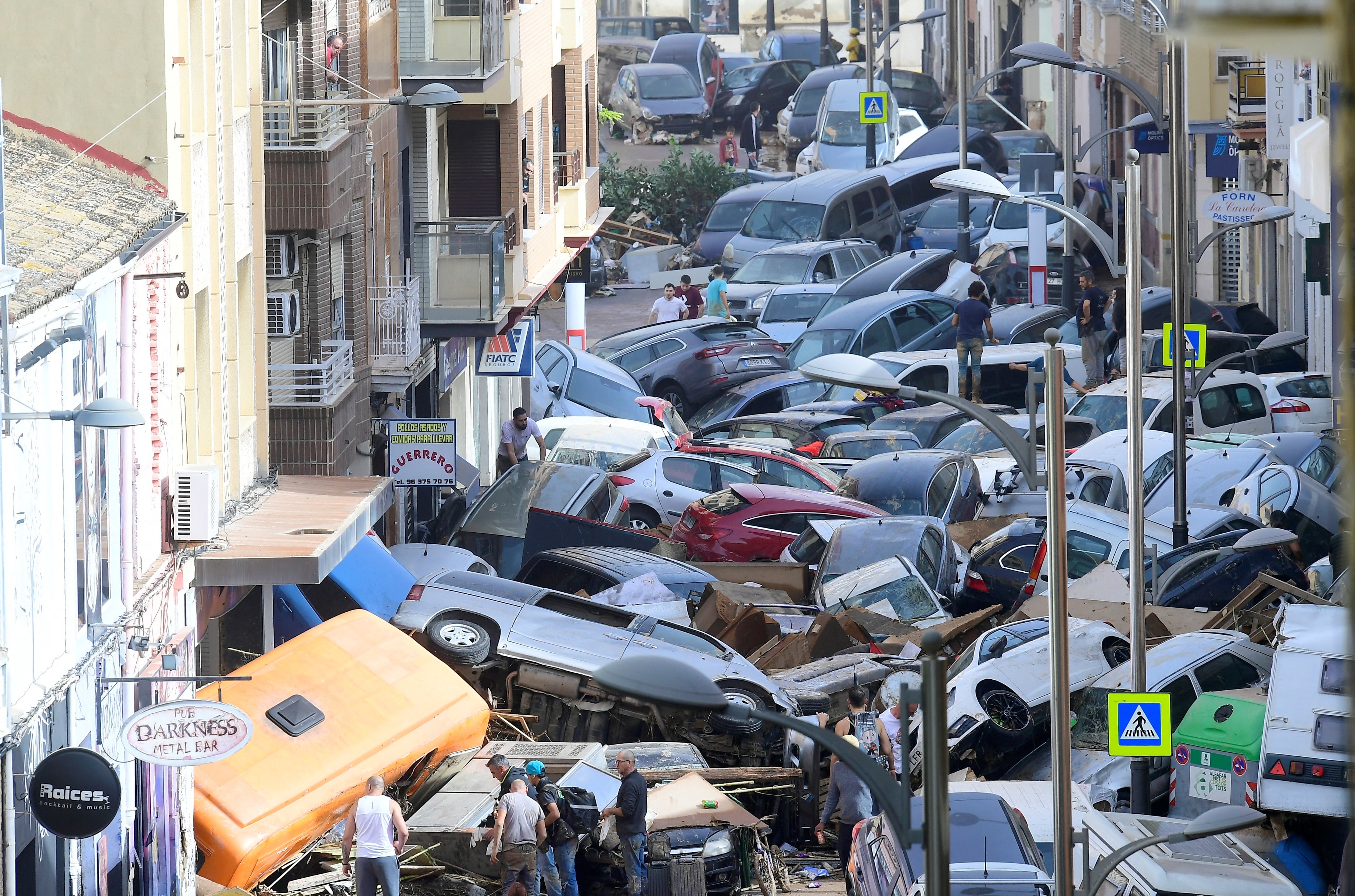 Pedestrians stand next to piled up cars following deadly floods in Sedavi, south of Valencia