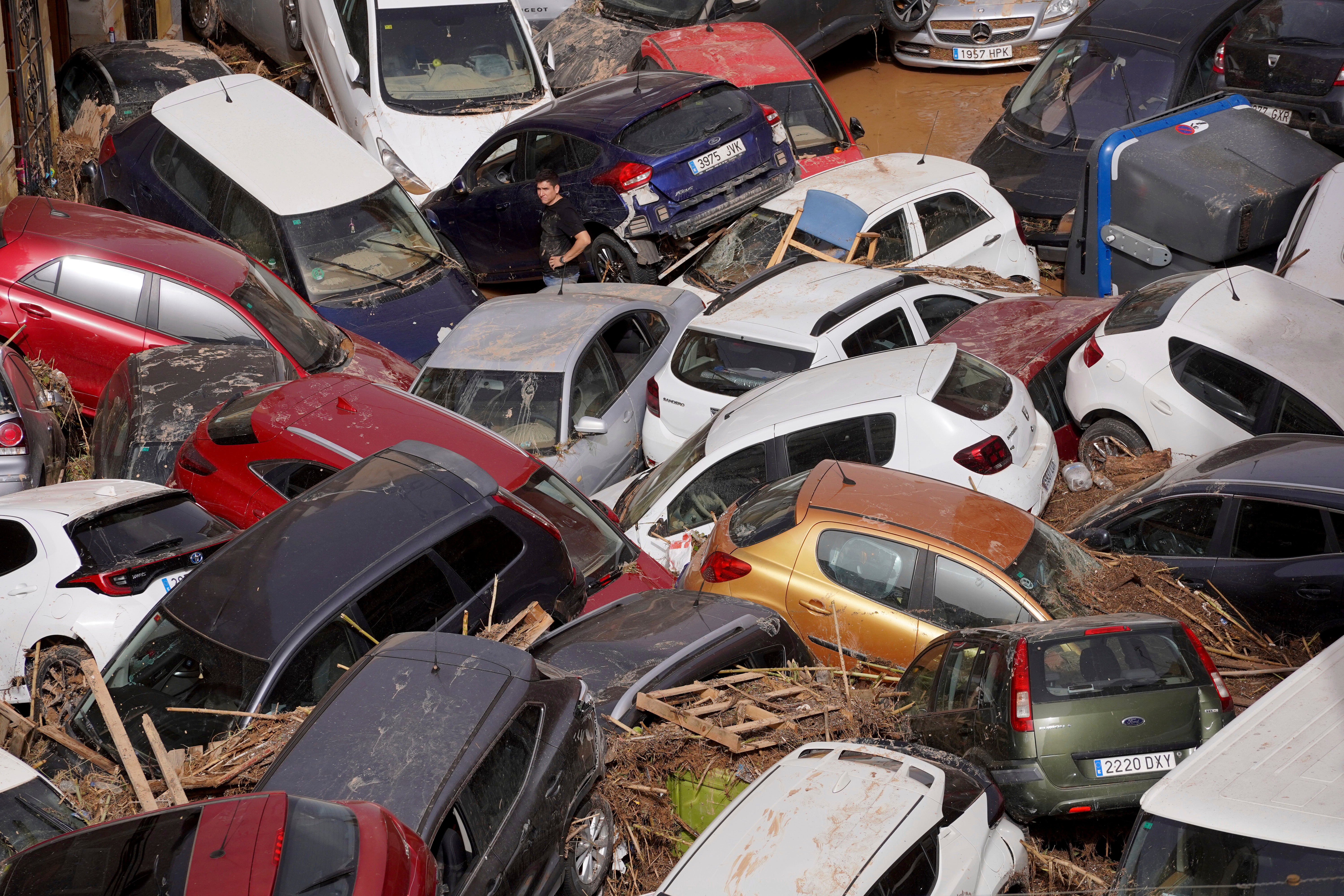 Residents look at cars piled up after being swept away by floods in Valencia