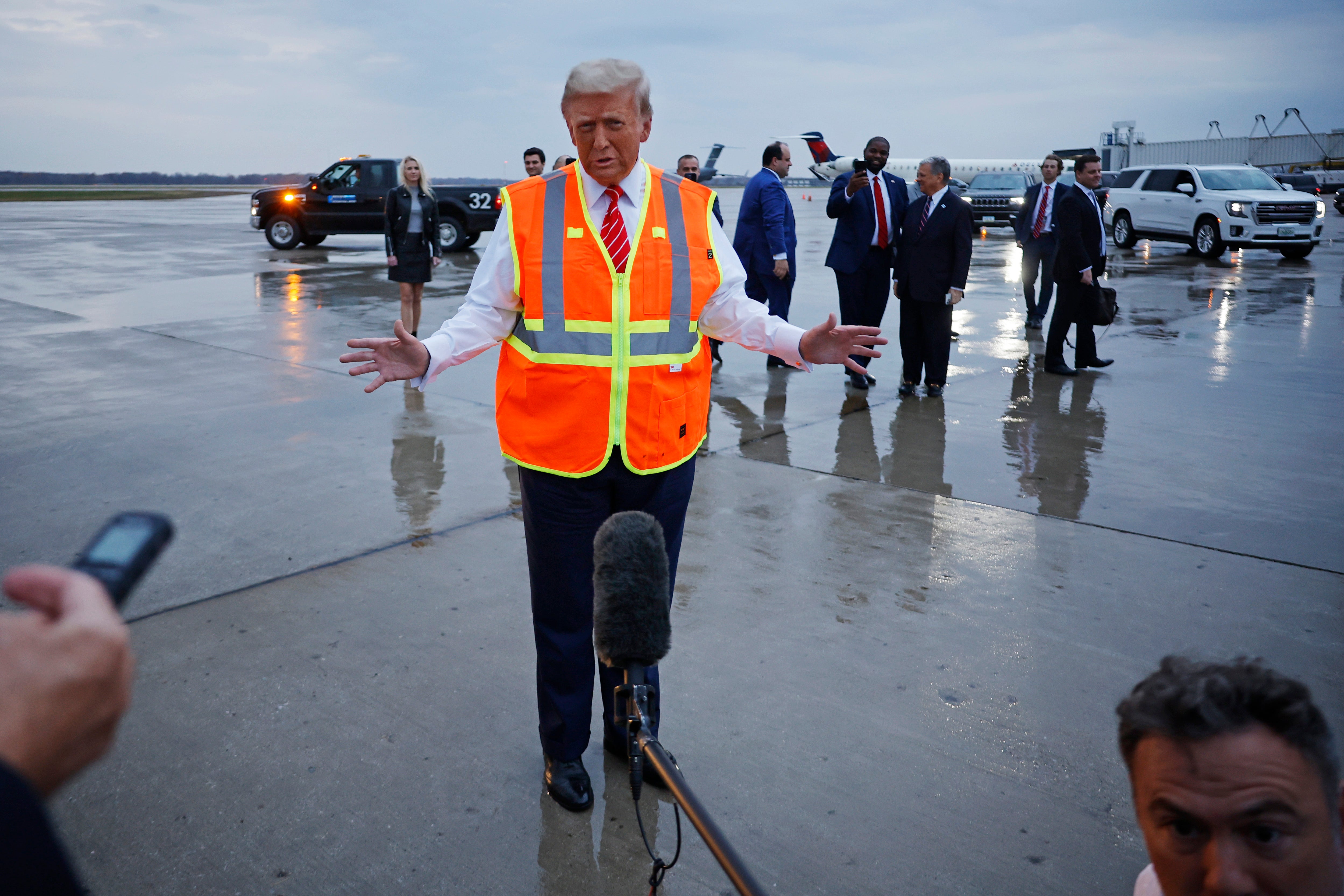 Donald Trump speaks to reporters while wearing a safety vest on the tarmac at Green Bay Austin Straubel International Airport on October 30, 2024, in Green Bay, Wisconsin. He saw his net worth decrease by $1.3bn in a single day on Wednesday