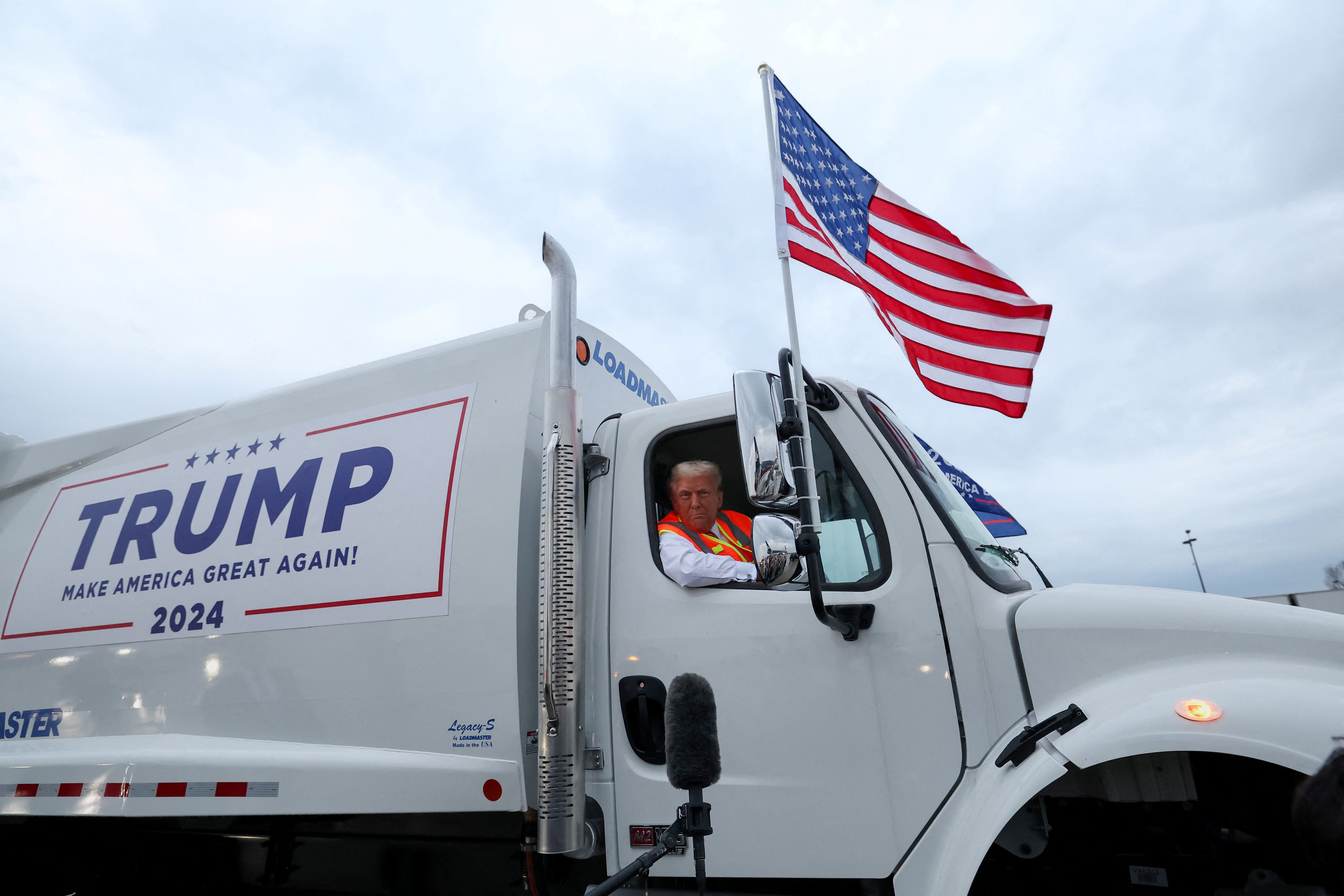 Donald Trump sits inside garbage truck as he wears a high-vis vest, on tarmac at Green Bay Austin Straubel International Airport