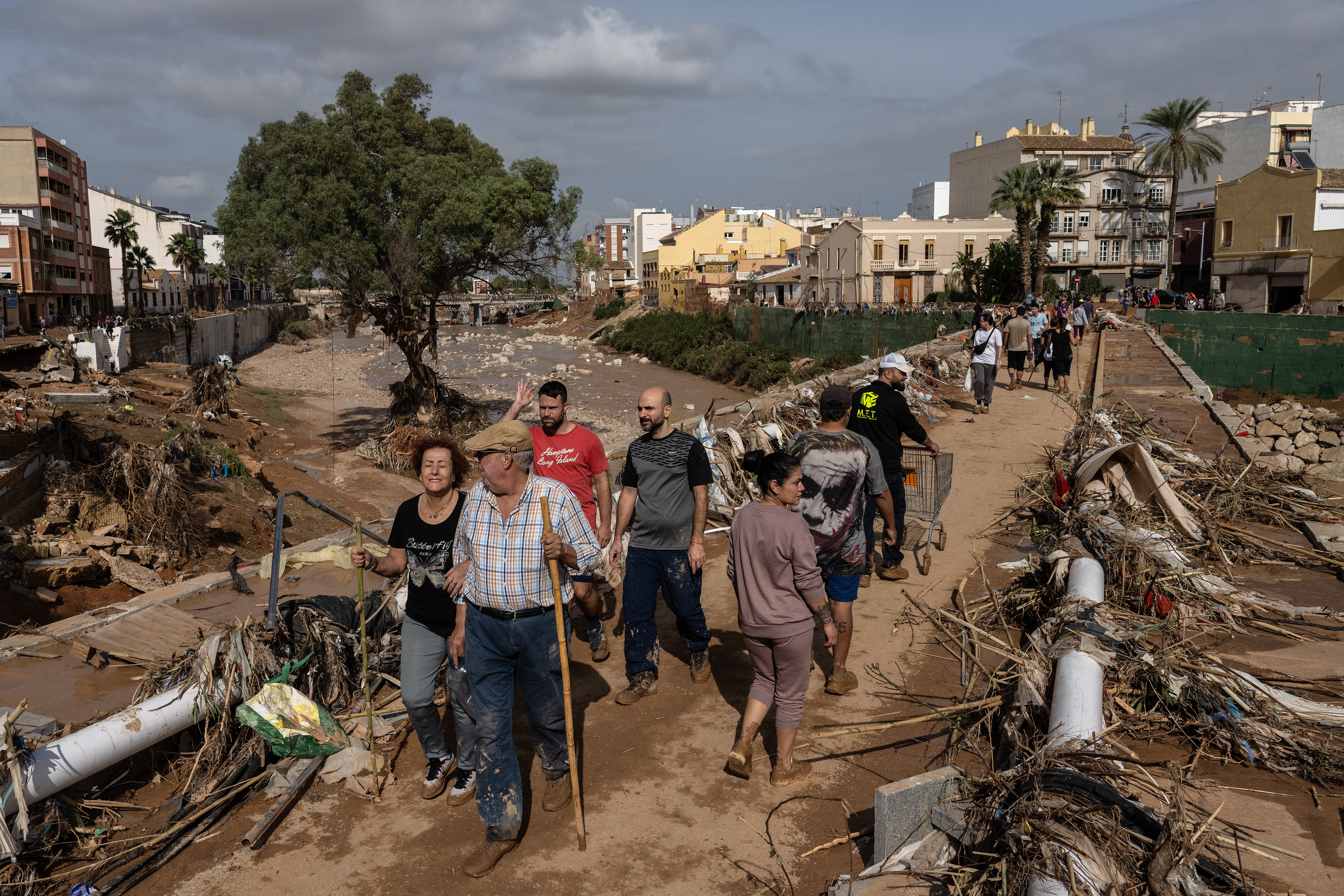 People cross a bridge through piles of debris after floods hit parts of the country in the Paiporta municipality of Valencia, Spain