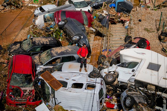 <p>Man stands among cars piled up by the floods in Valencia, Spain</p>