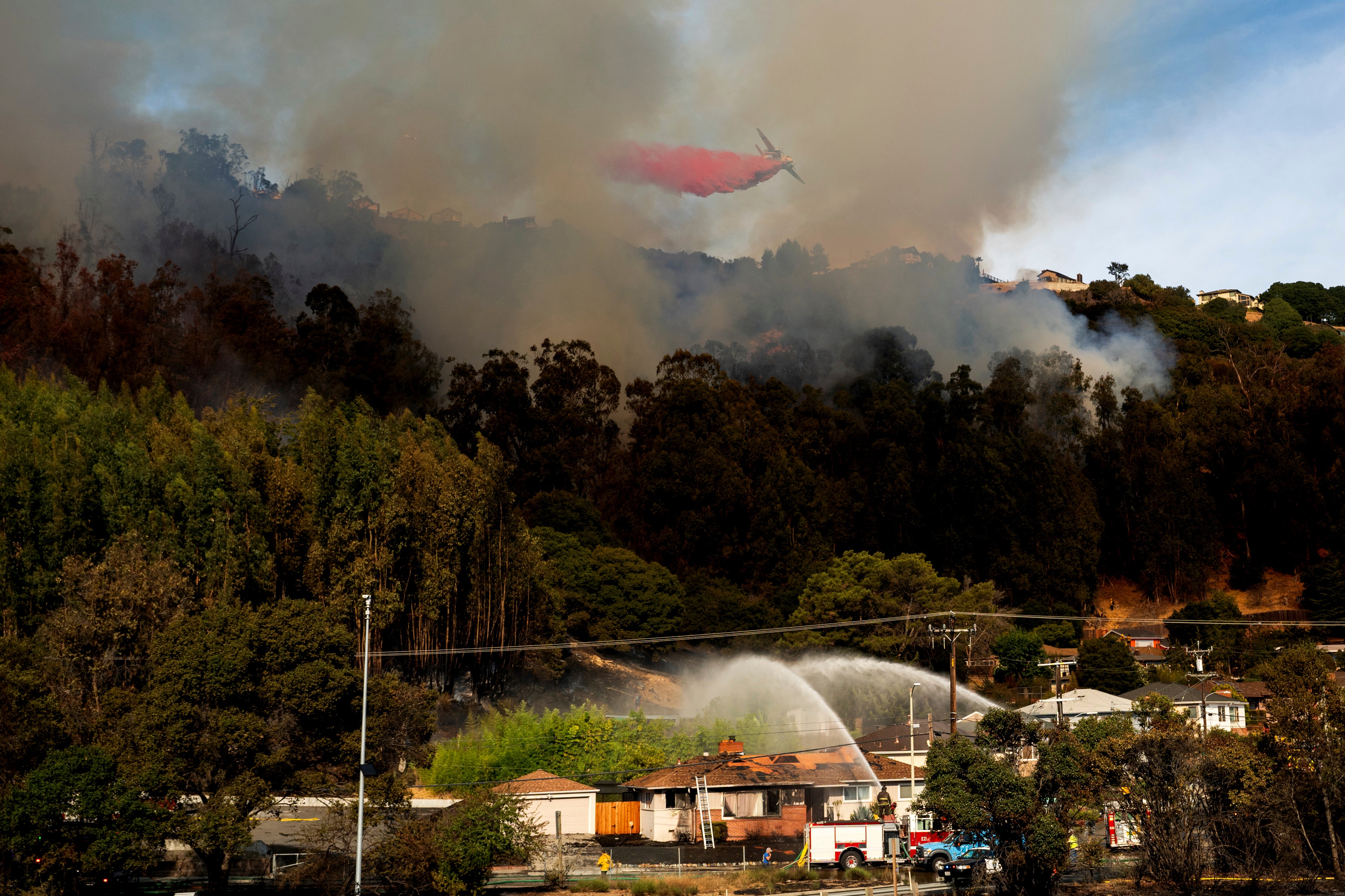 A grass fire burns above Interstate 580 in Oakland, California, earlier this month. October has seen toasty temperatures made more likely by climate change across the US. California and Washington voters will head to the polls to vote on climate legislation next week.