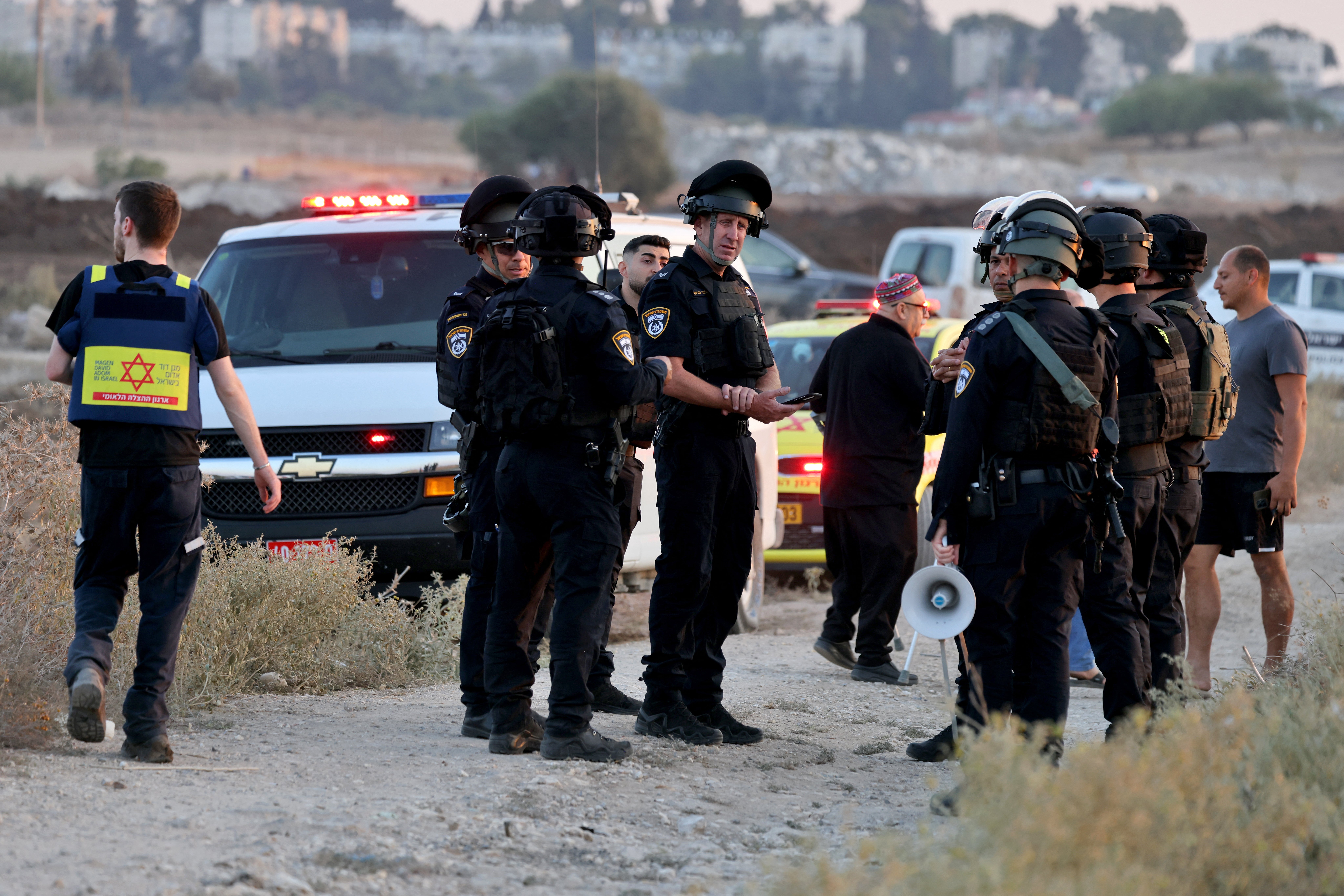 Israeli security forces and first responders stand at the site where a rocket fired from Lebanon hit an area near Kiryat Ata in northern Israel's Haifa district