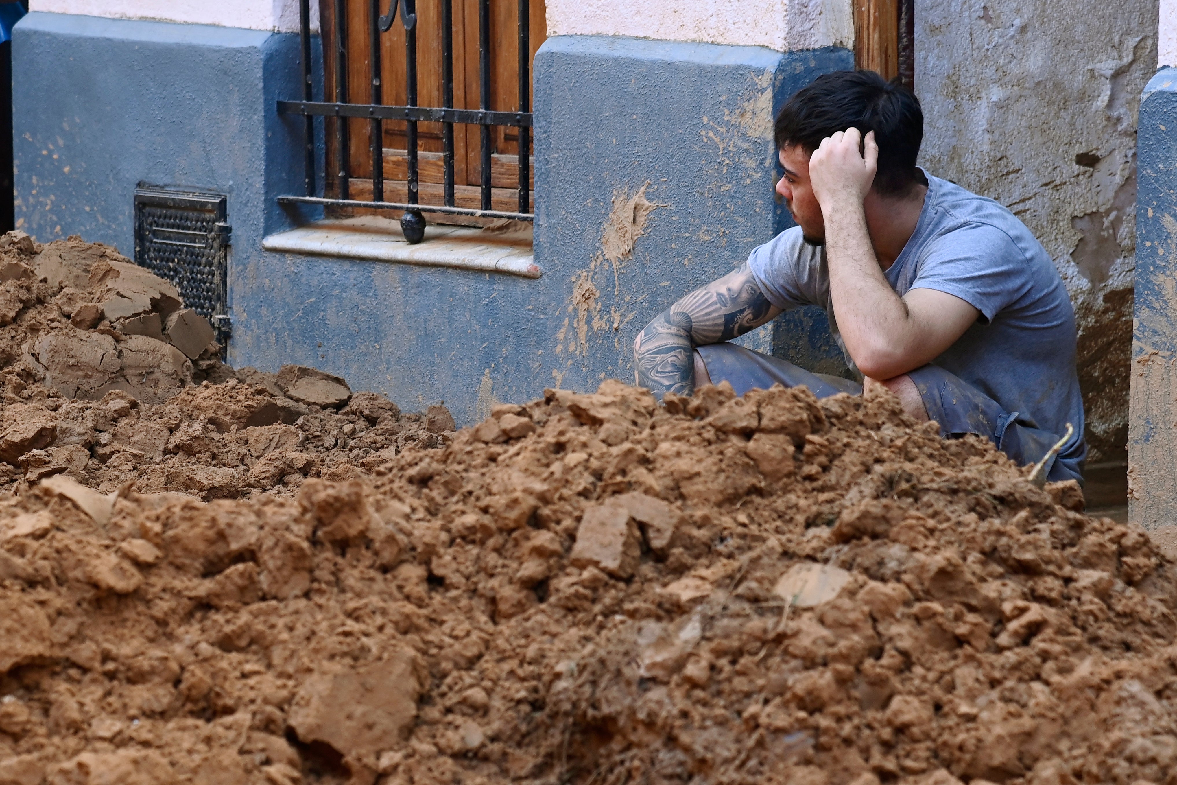 A man sits behind a big pile of mud following the devastating effects of flooding on Paiporta