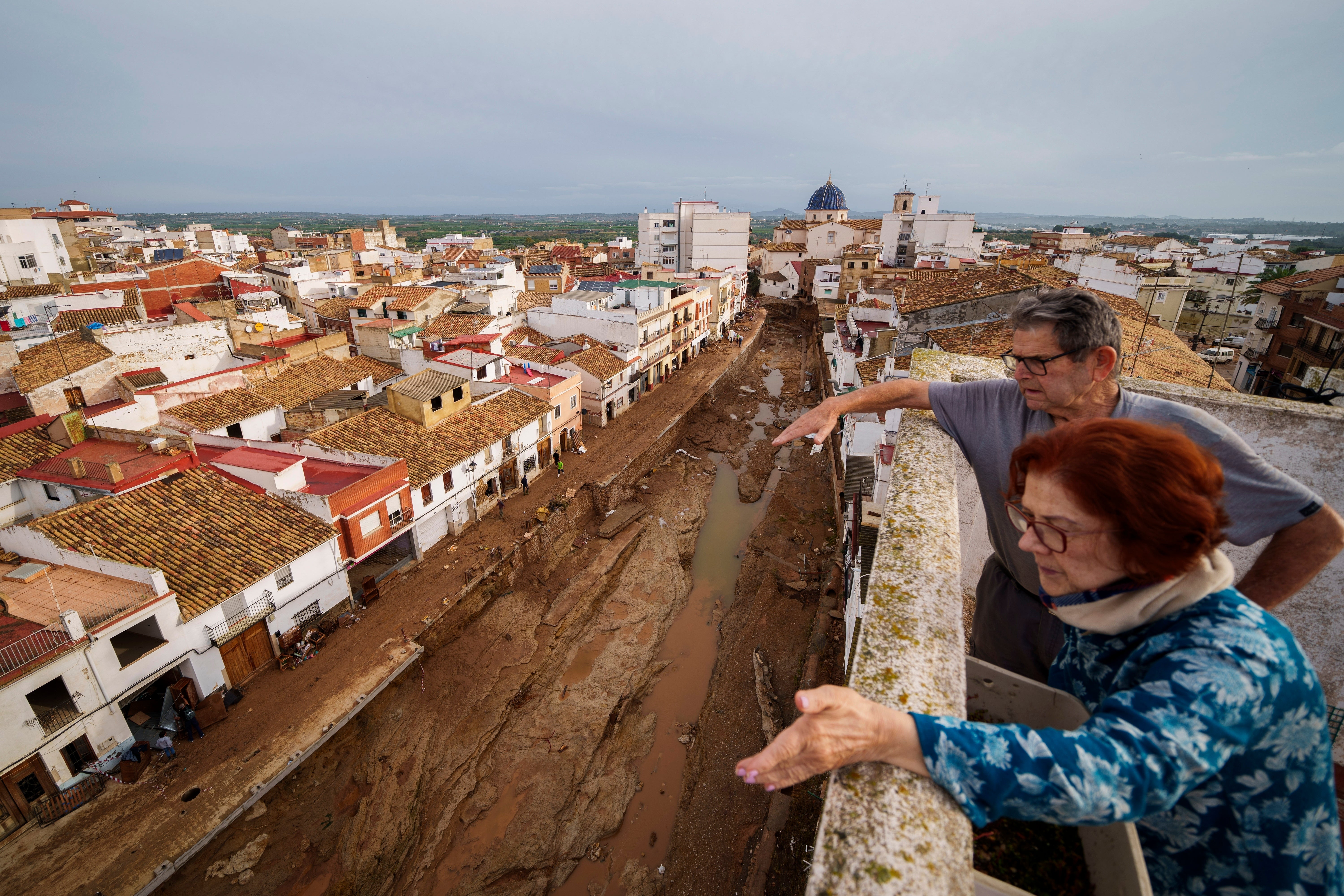 Two people look out over an area affected by floods in Chiva, Spain