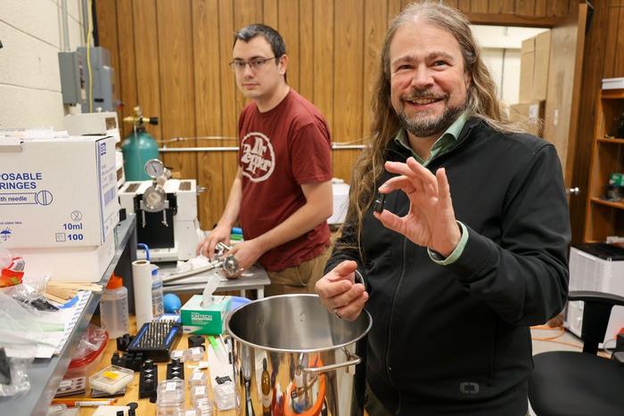 Ph.D. candidate Keegan Walkup, left, and physicist Patrick Huber work in the new lab that Huber is establishing to look for evidence of dark matter traces inside the crystal lattice structures of old rocks.