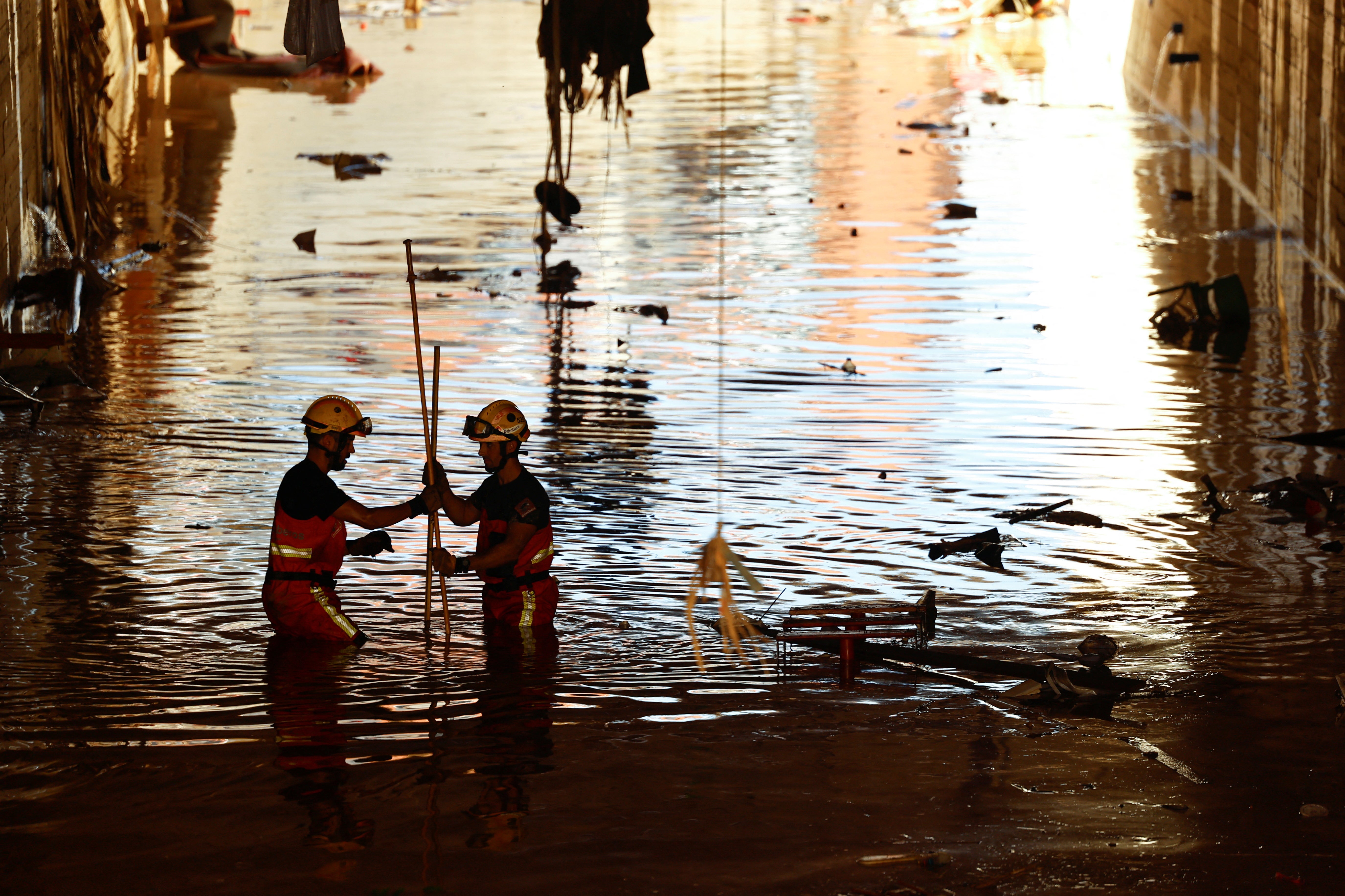 Firefighters wade in water as they search for victims under a bridge