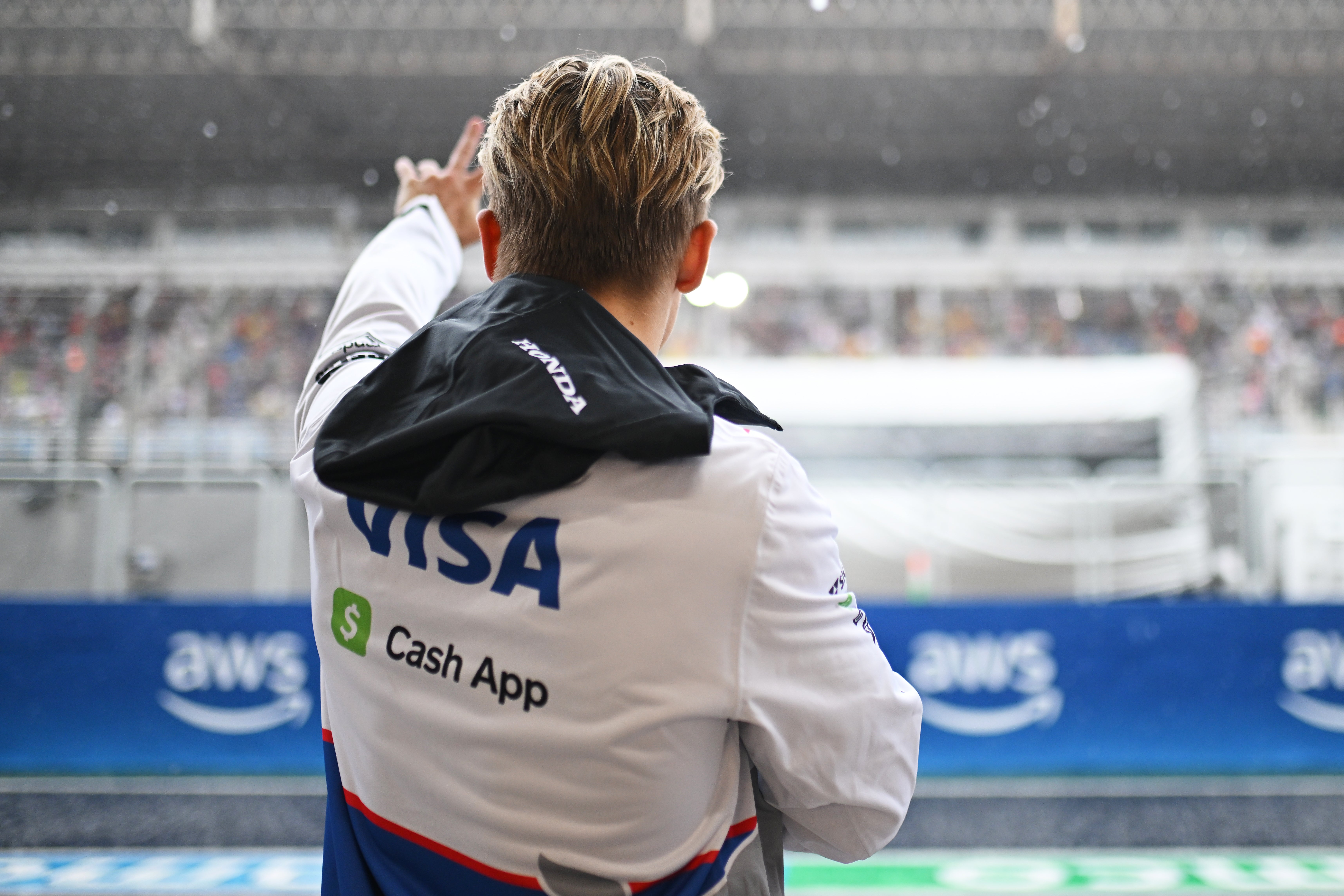 Liam Lawson waves to the fans amid the rain at Interlagos