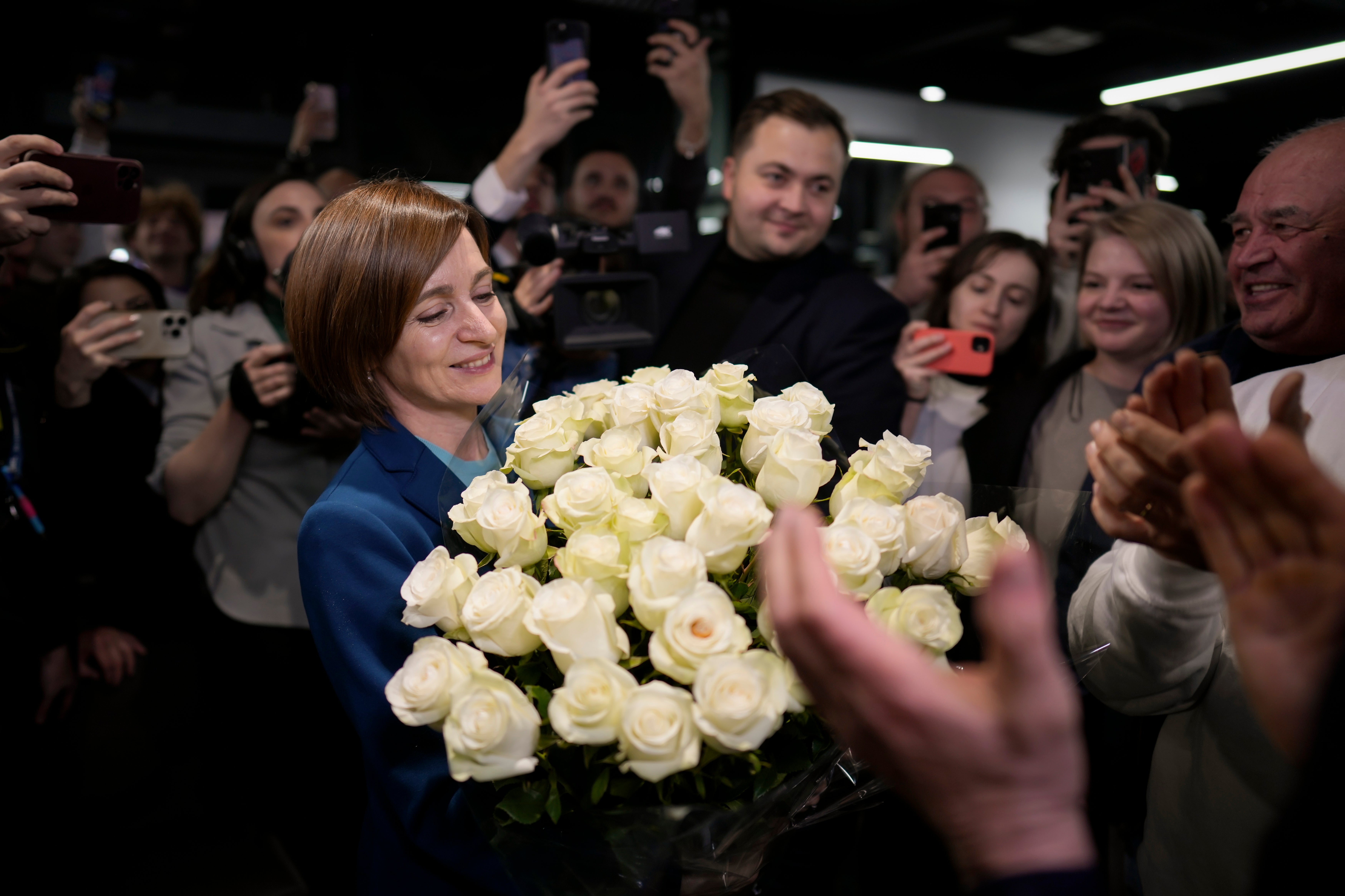 Moldova’s President Maia Sandu smiles while holding a bouquet of flowers as she celebrates with supporters the preliminary results of presidential election runoff