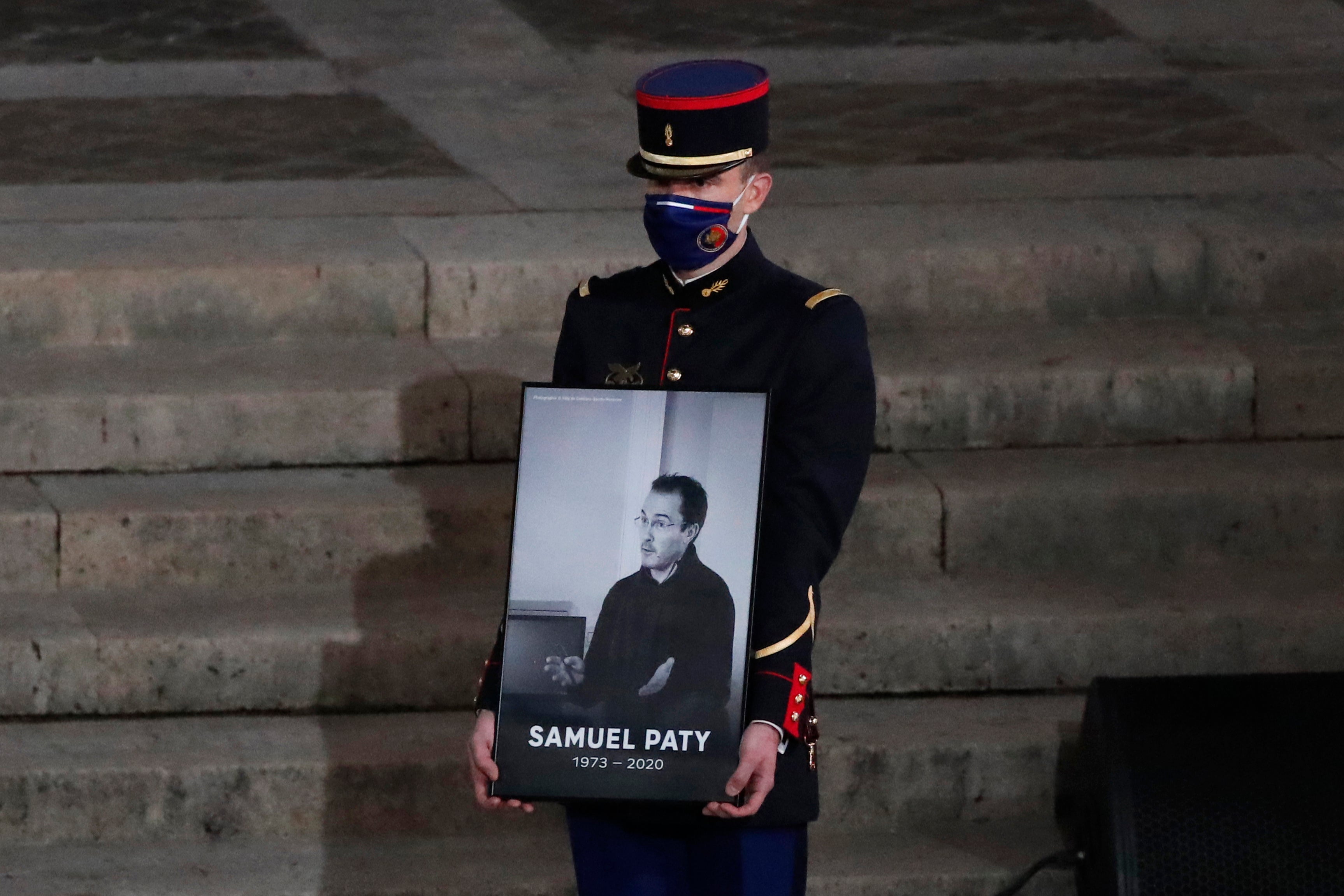 A Republican Guard holds a portrait of Samuel Paty in the courtyard of the Sorbonne university