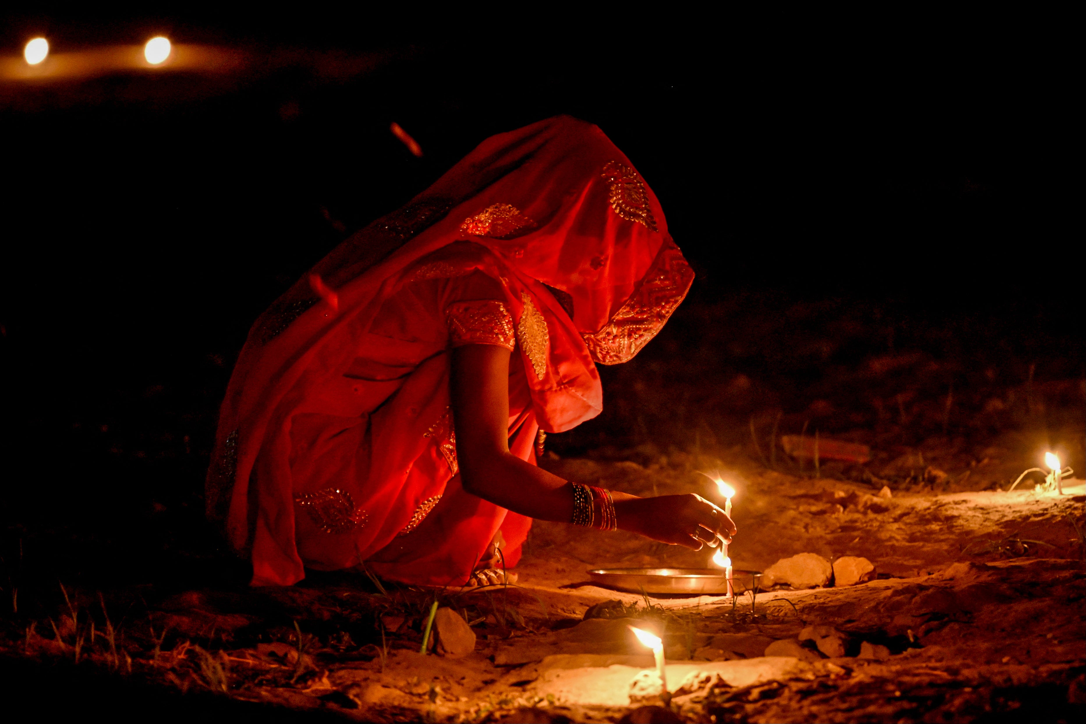 A woman lights candles in front of her house during the celebrations to mark Diwali