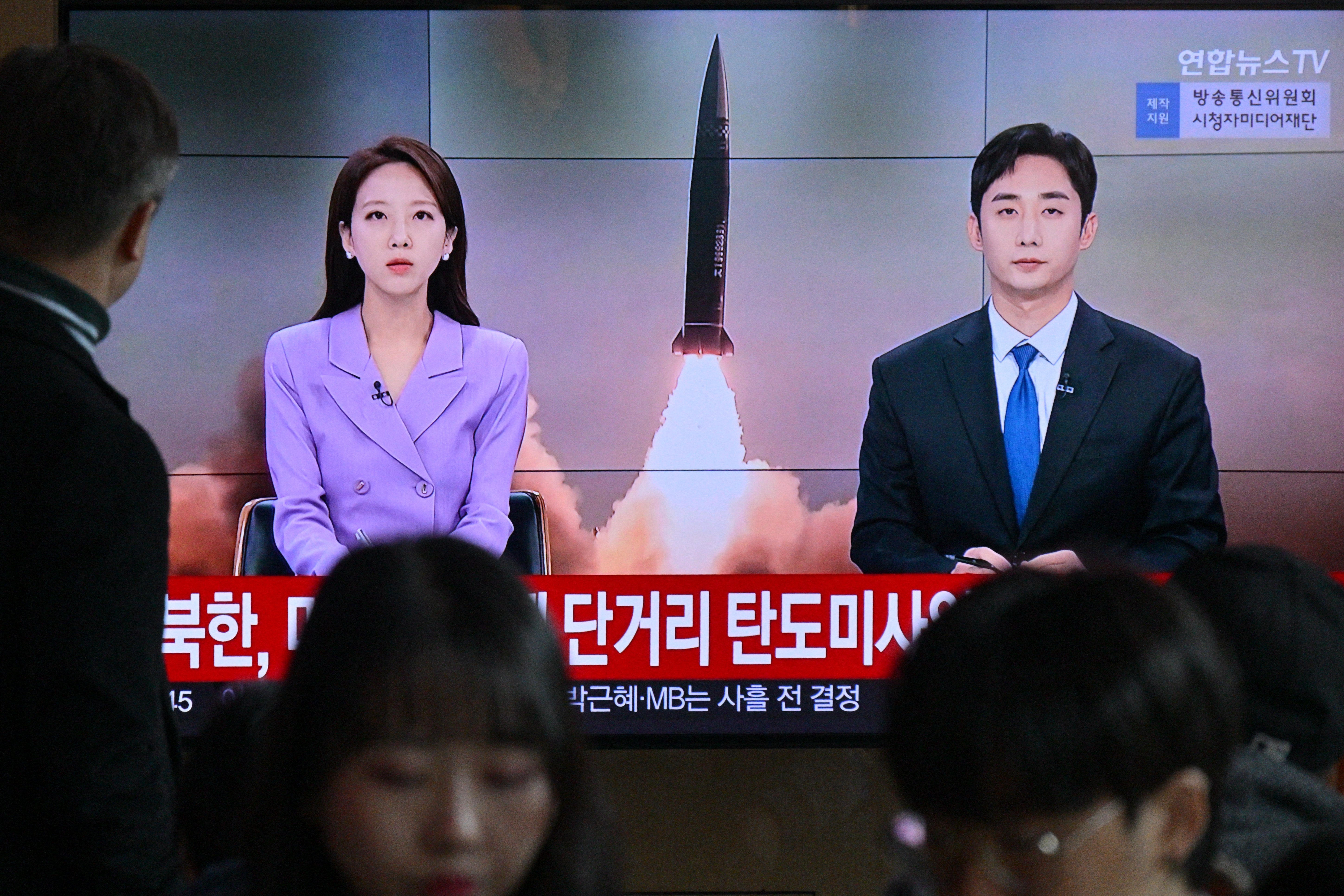 A man watches a television showing a news broadcast with file footage of a North Korean missile test