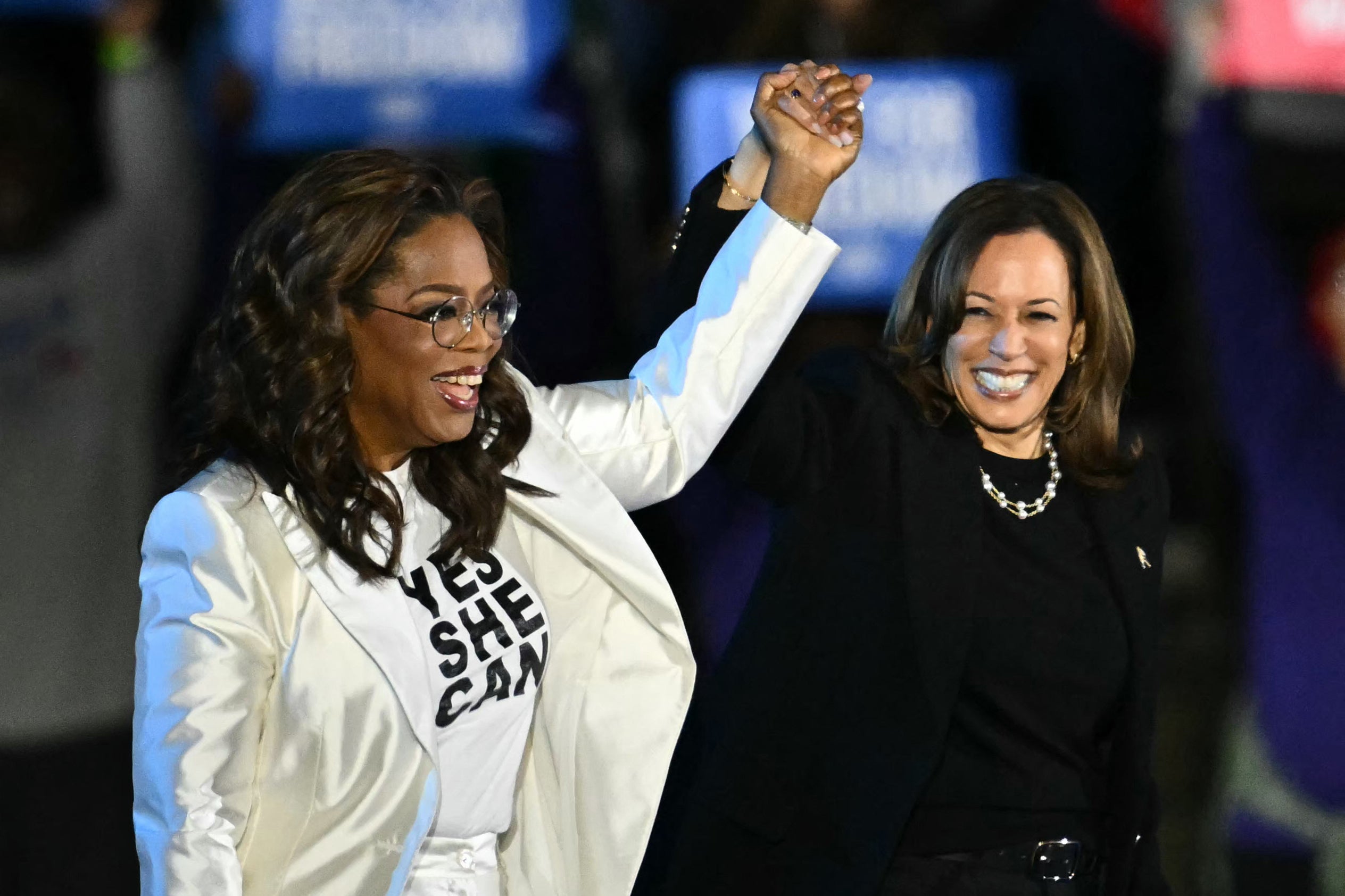 Oprah Winfrey (L) holds up Vice President Kamala Harris’ hand as she arrive onstage during a campaign rally on the Benjamin Franklin Parkway in Philadelphia, Pennsylvania