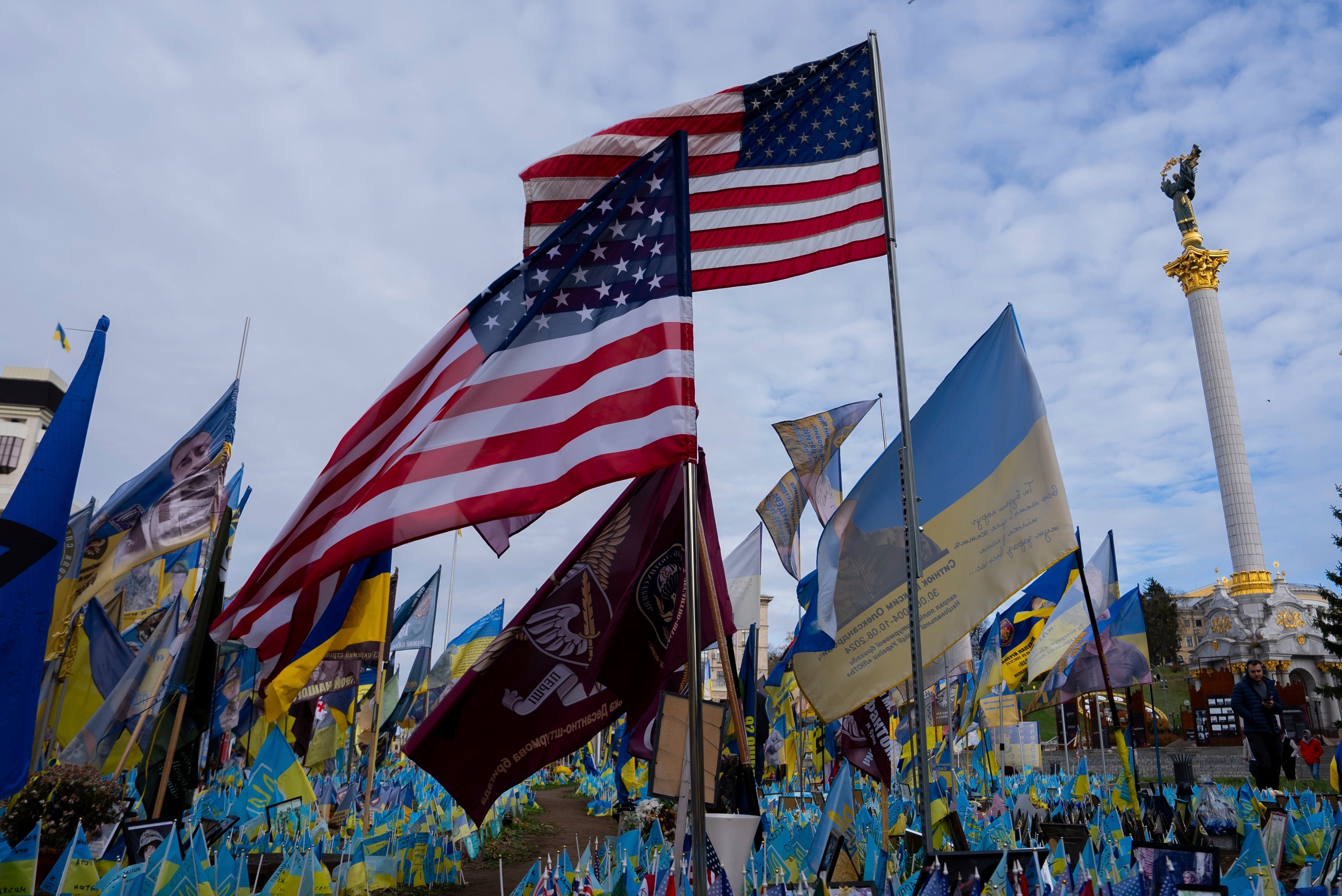 American and Ukrainian flags placed in honour of fallen servicemen flutter in the wind in front of statue in central square, in Kyiv, Ukraine