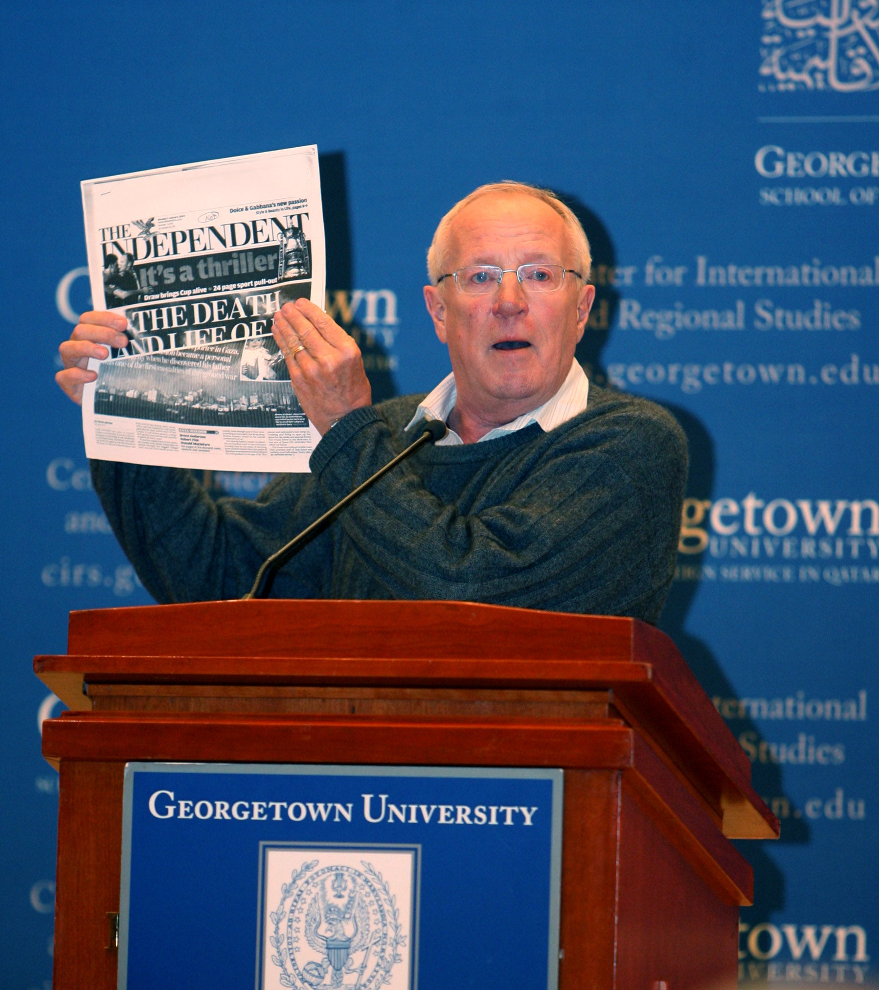 Fisk holding the front page of The Independent during a speech at Georgetown University