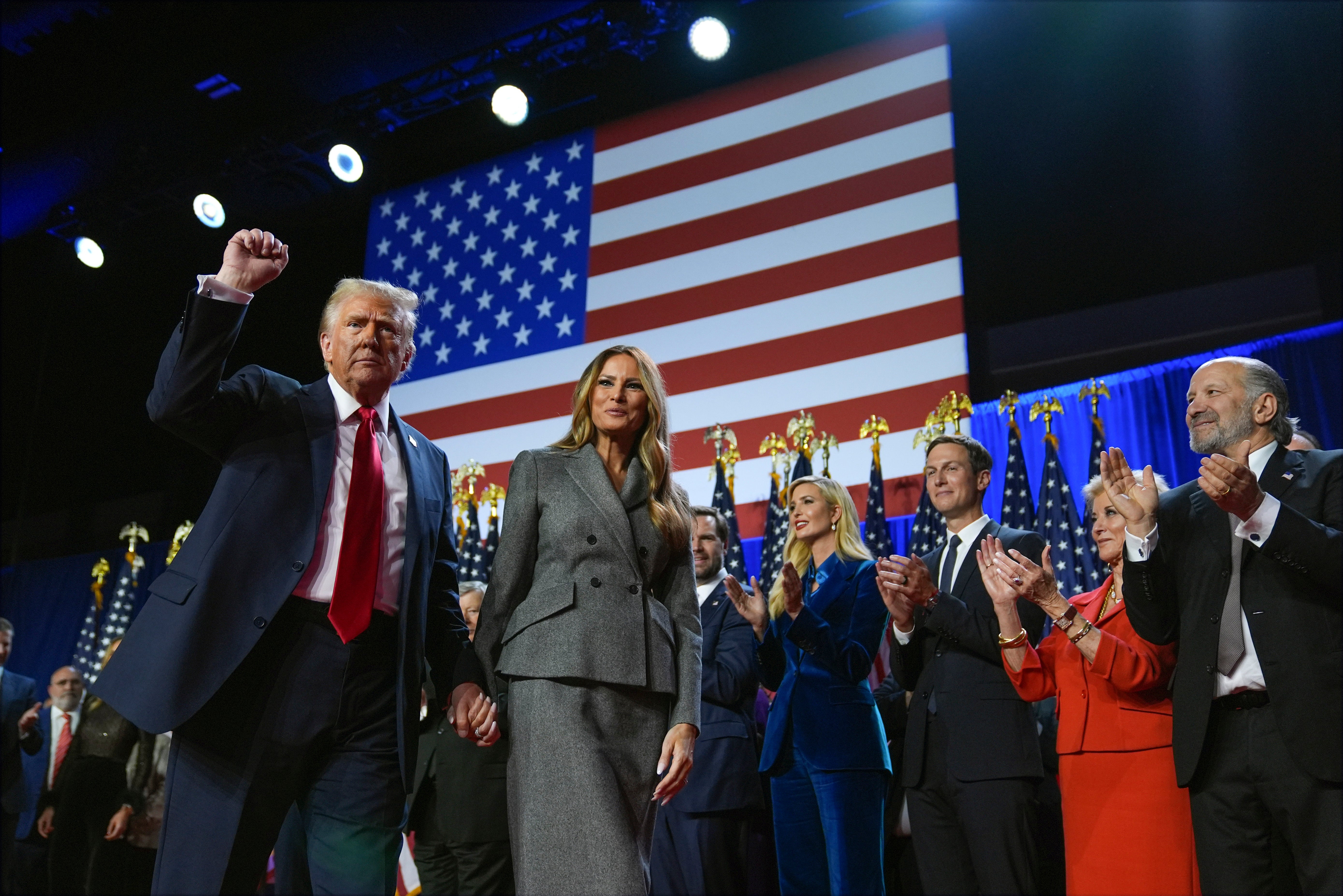 Republican presidential nominee former President Donald Trump gestures as he walks with former first lady Melania Trump