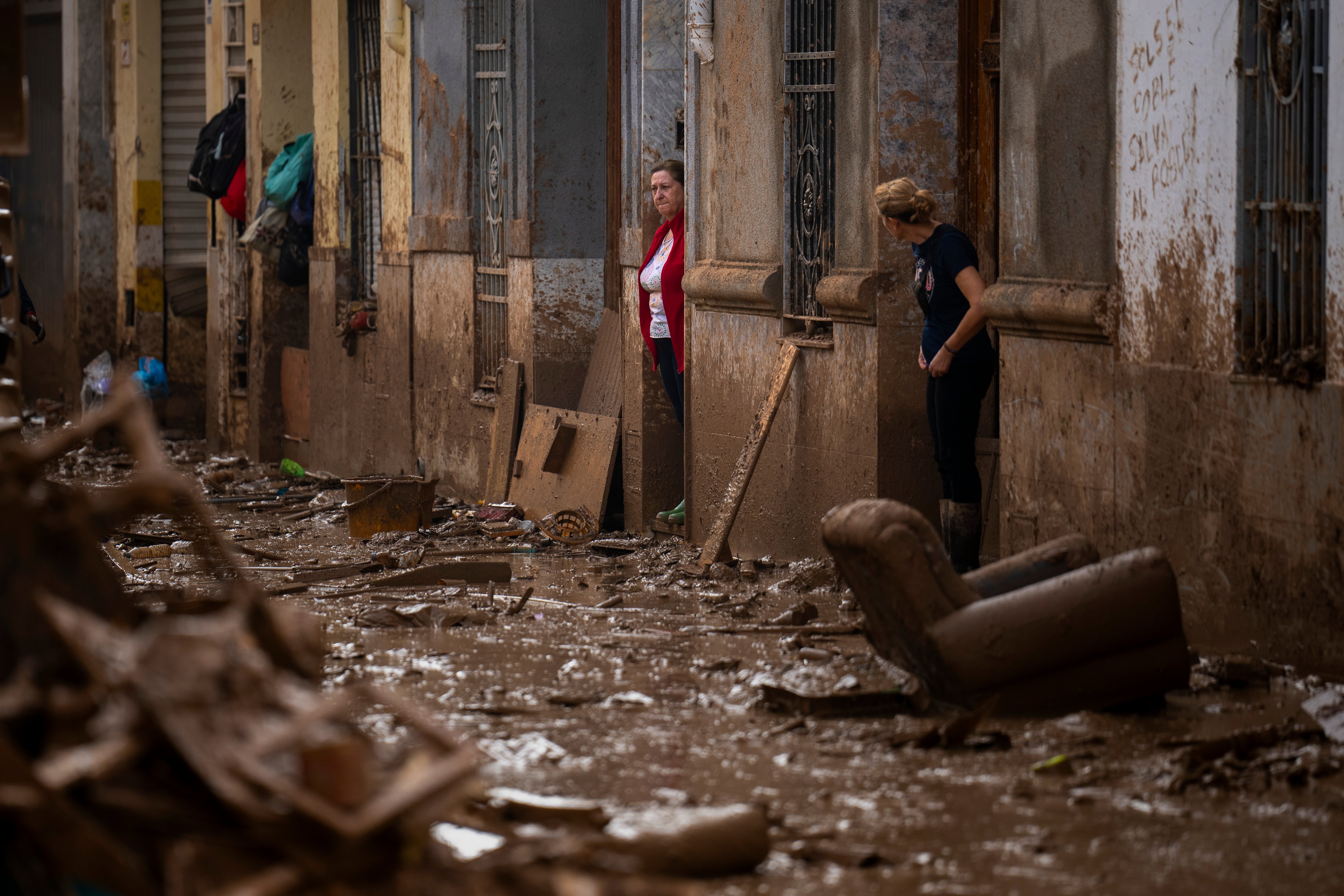 Women stand at the entrance of their houses affected by flooding in Masanasa, Valencia, Spain