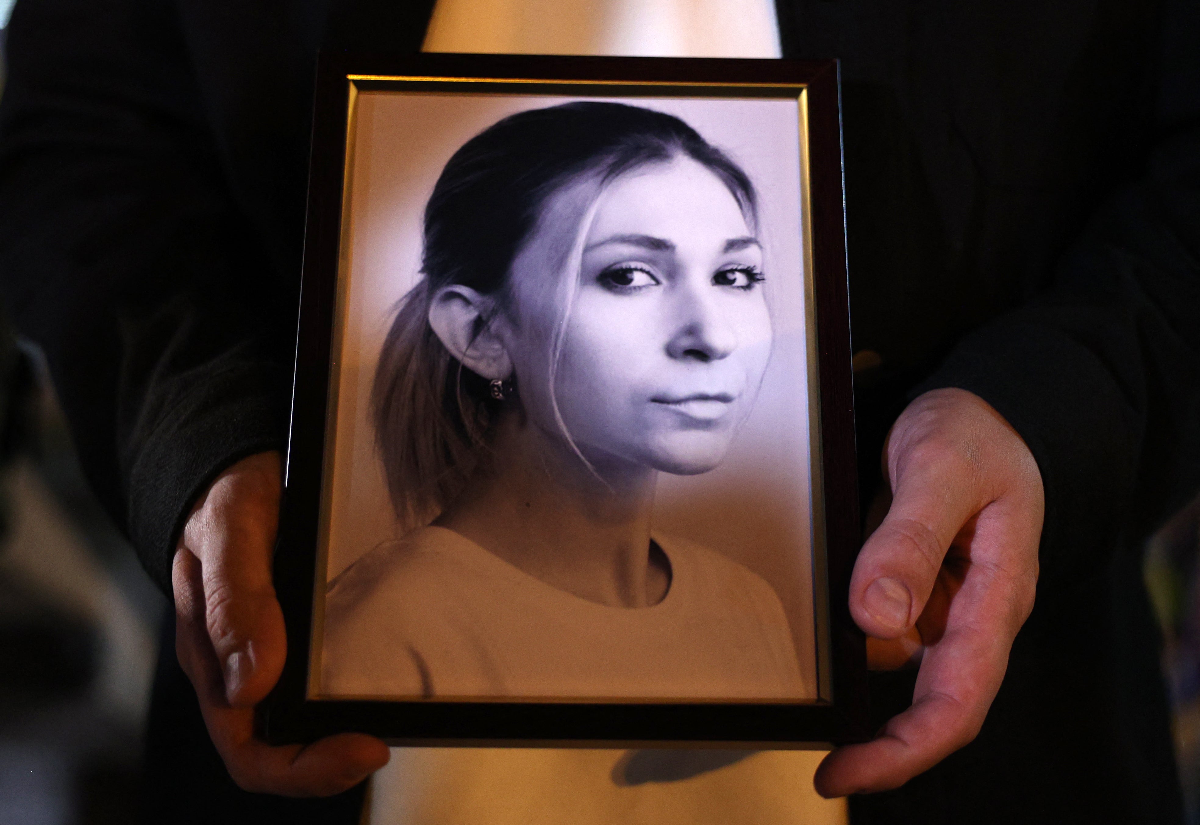 A colleague of Ukrainian journalist Victoria Roshchyna holds a photograph of her during an event in honour of her memory at a makeshift memorial for fallen Ukrainian soldiers, at Independence Square in Kyiv, on 11 October 2024