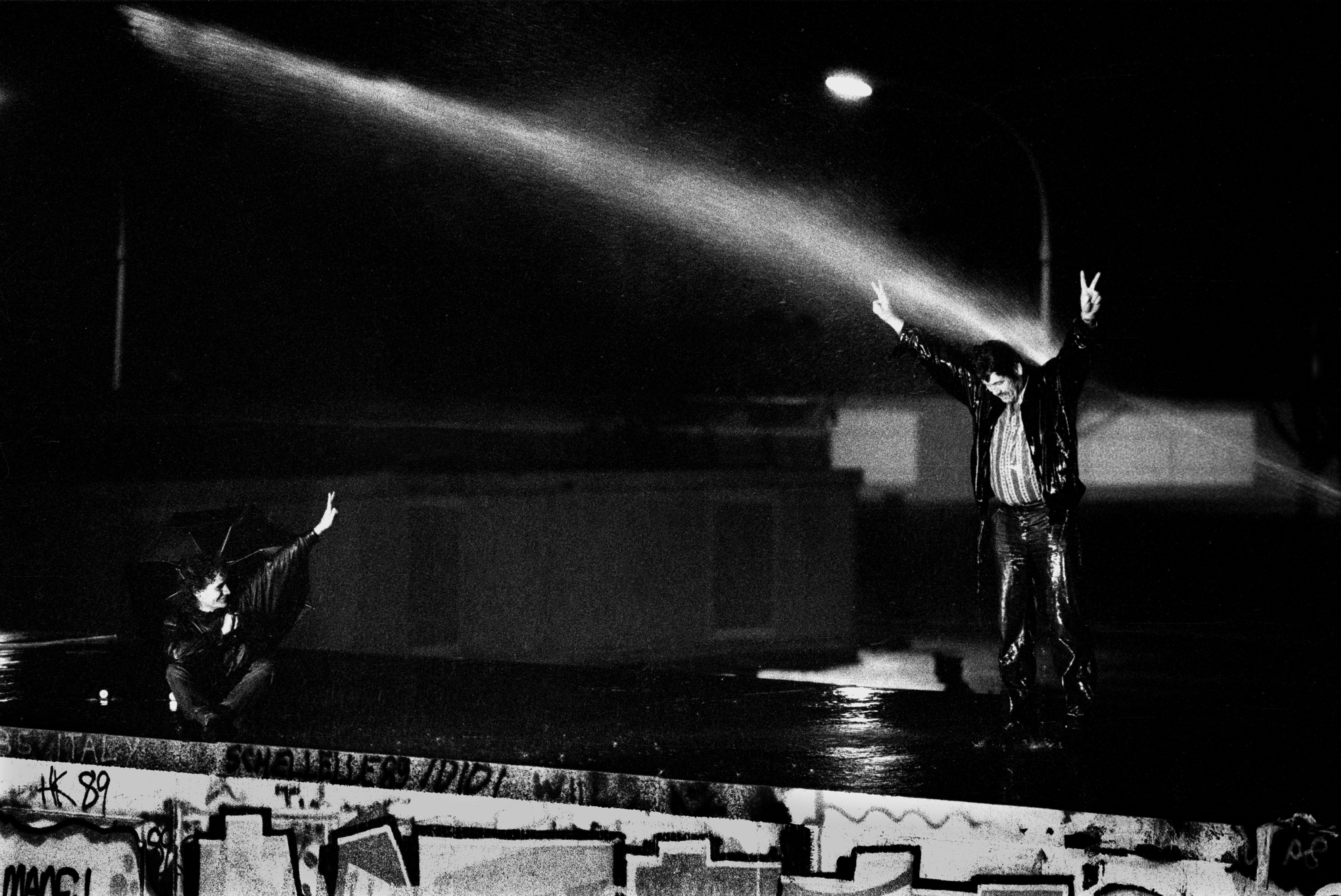 Opening night: people scale the Berlin Wall at the Brandenburg Gate as East German border guards try to hose them down