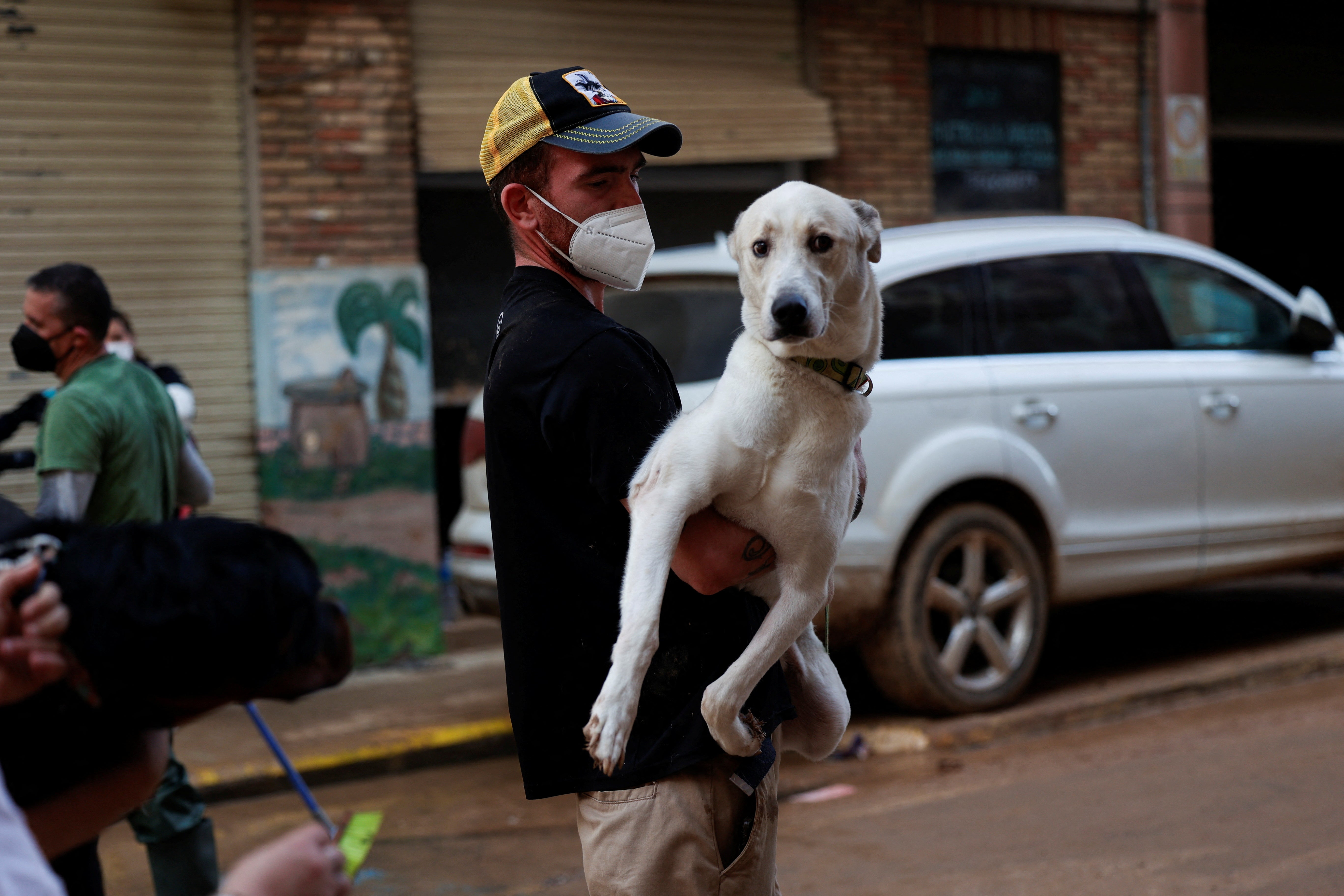 A local man carries his dog to a relative's home in another town away from the disaster-affected area in Paiporta, Valencia