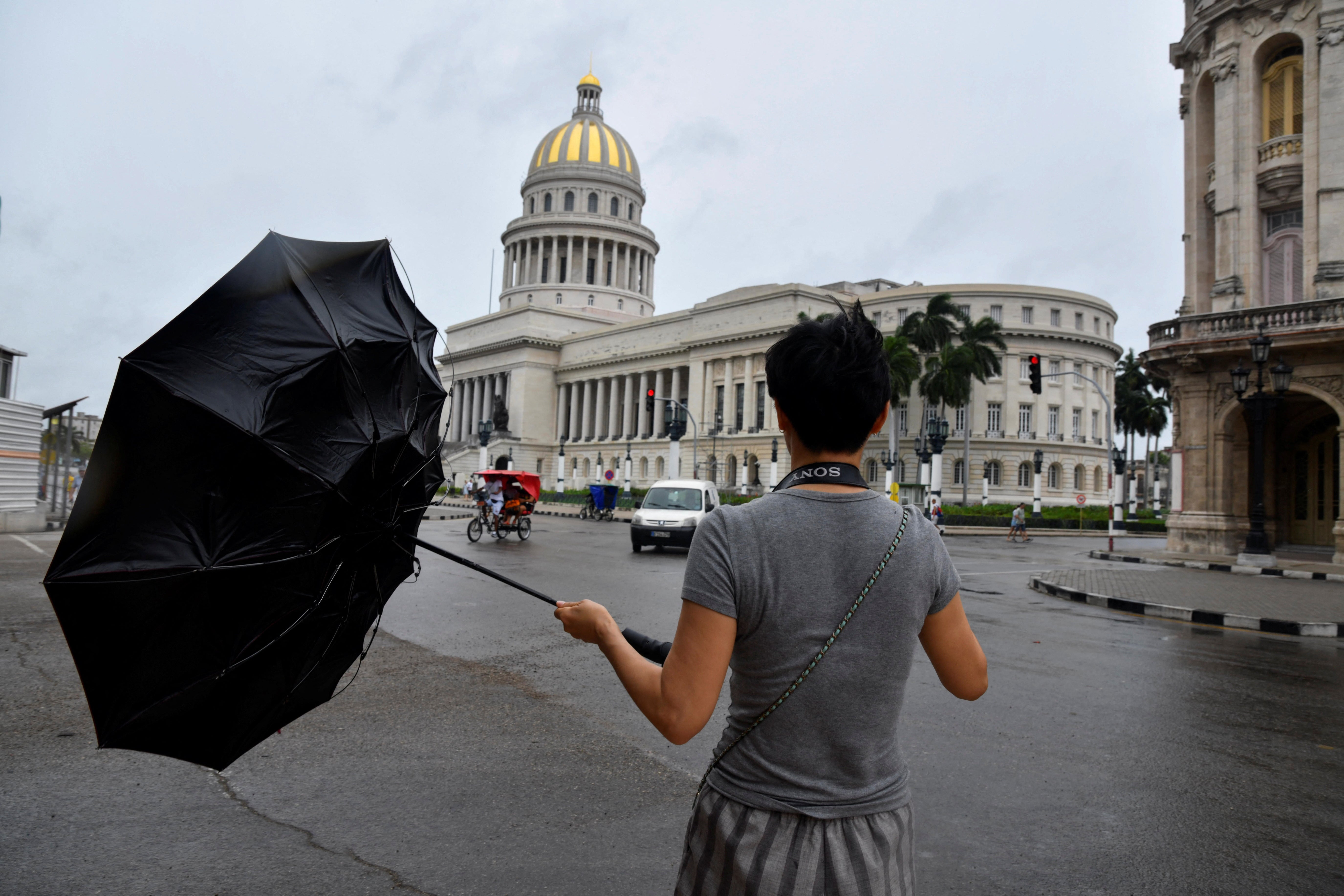 A tourist from China tries to hold his umbrella as Hurricane Rafael passes by Havana, Cuba, on Wednesday. The hurricane is heading westward through the weekend.