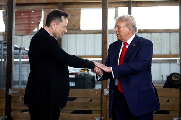 Elon Musk shakes hands with Donald Trump