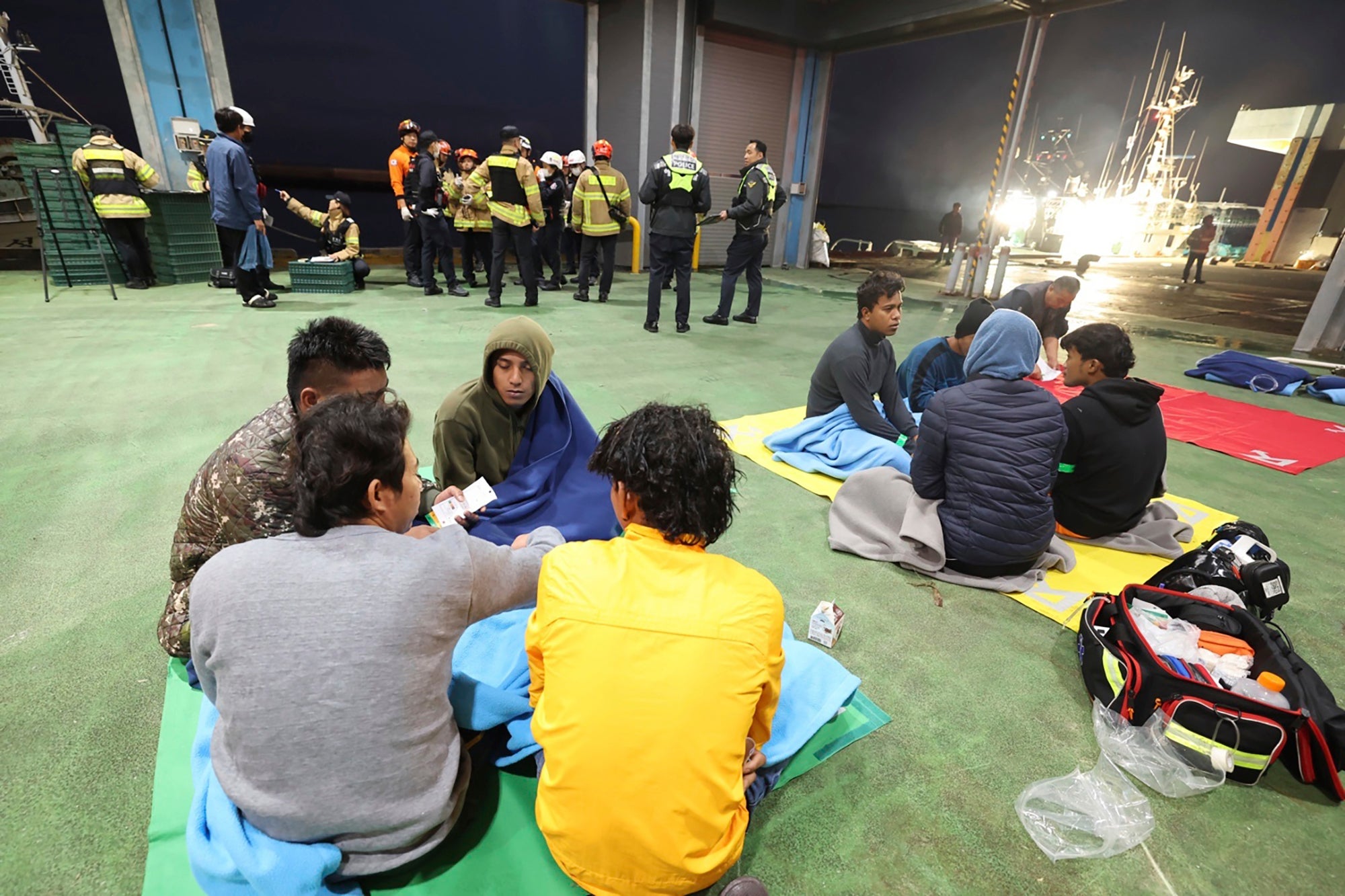 Rescued crew members of a fishing boat wait for transfer to a hospital at a port on Jeju Island, South Korea, on 8 November 2024