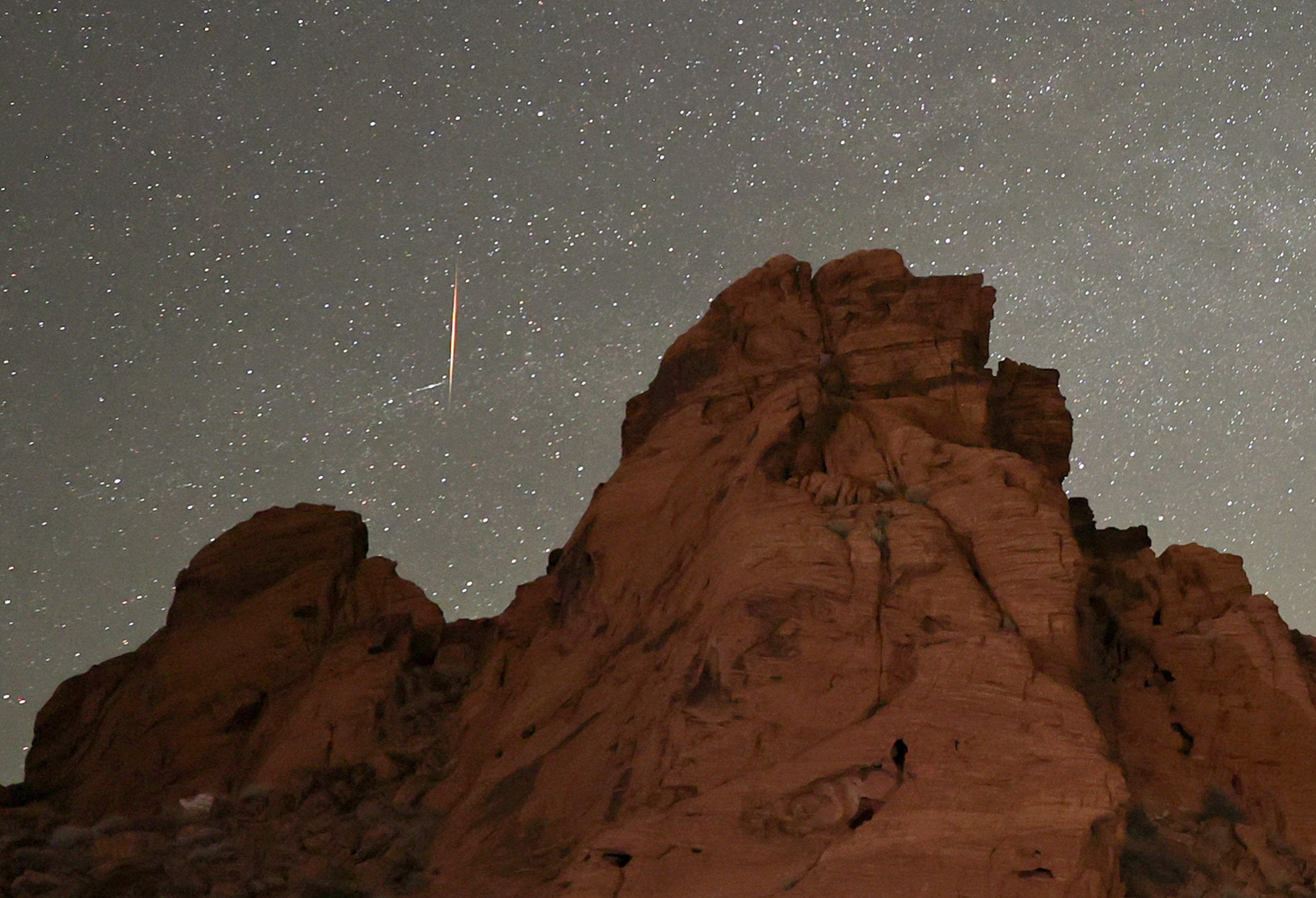 A meteor streaks above sandstone formations in Nevada as the Earth passes through the debris trails of a broken comet