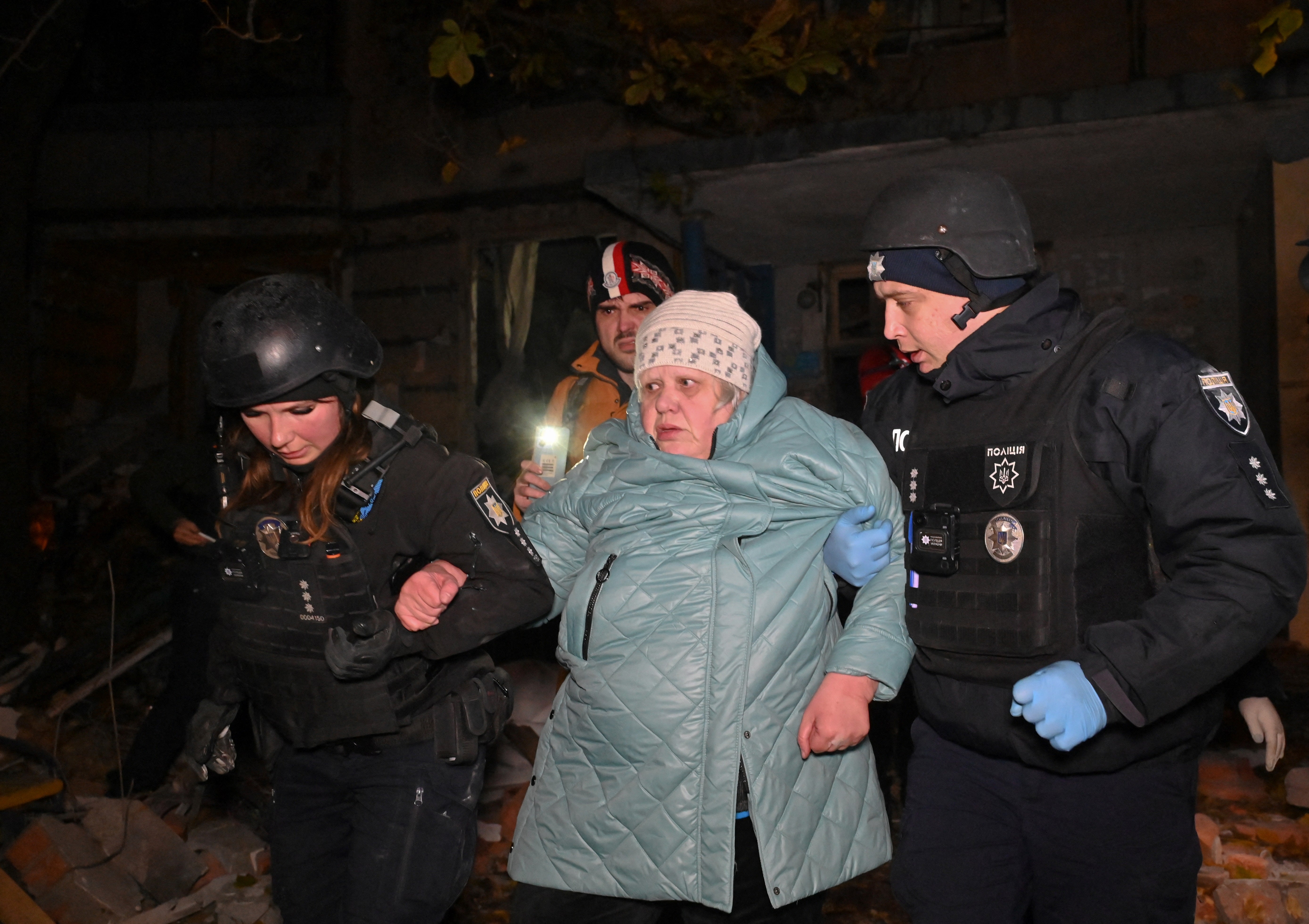 Ukrainian policemen help local residents to leave a multi-story building, damaged after an airstrike in Kharkiv on 8 November 2024