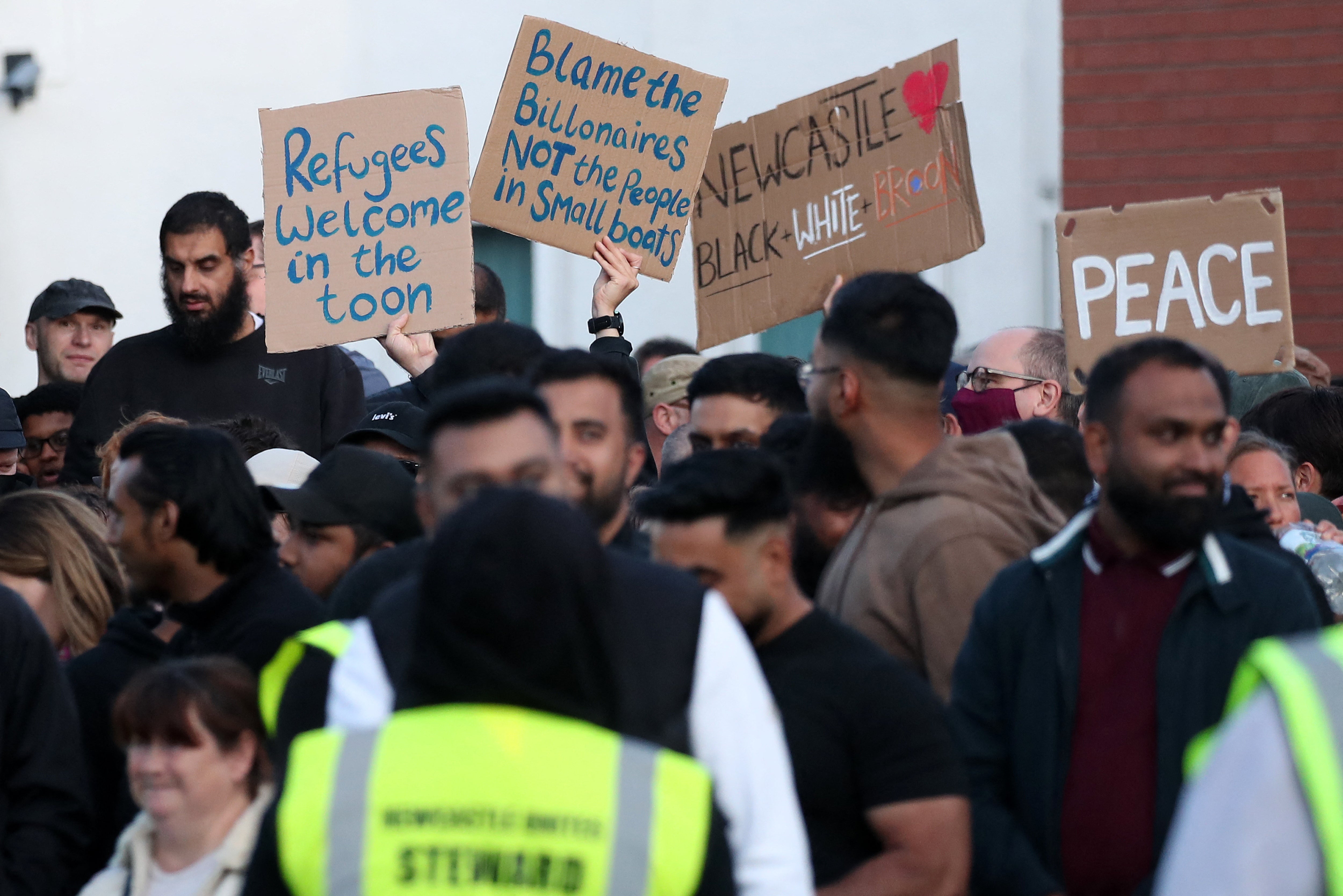 People hold pro-refugee, anti-racist placards as they attend a counter demonstration against an anti-immigration protest called by far-right activists, outside the United Immigration Services offices at The Beacon in Newcastle-upon-Tyne, north-east England on August 7, 2024