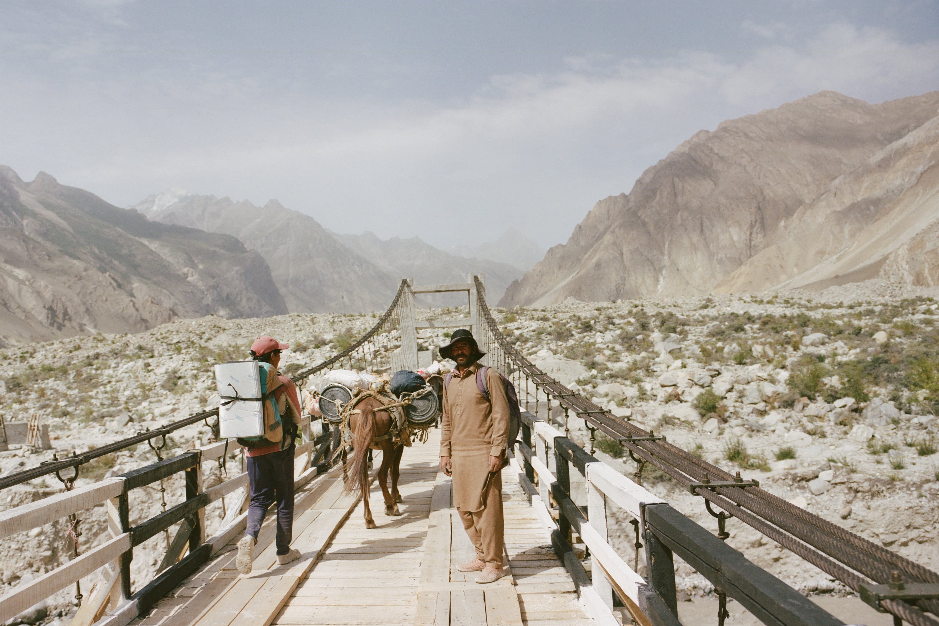 Sufi Hussain, the group’s head porter, and Ibrahim, another porter, crossing a bridge at Jhola across the Dumordo River with the mule