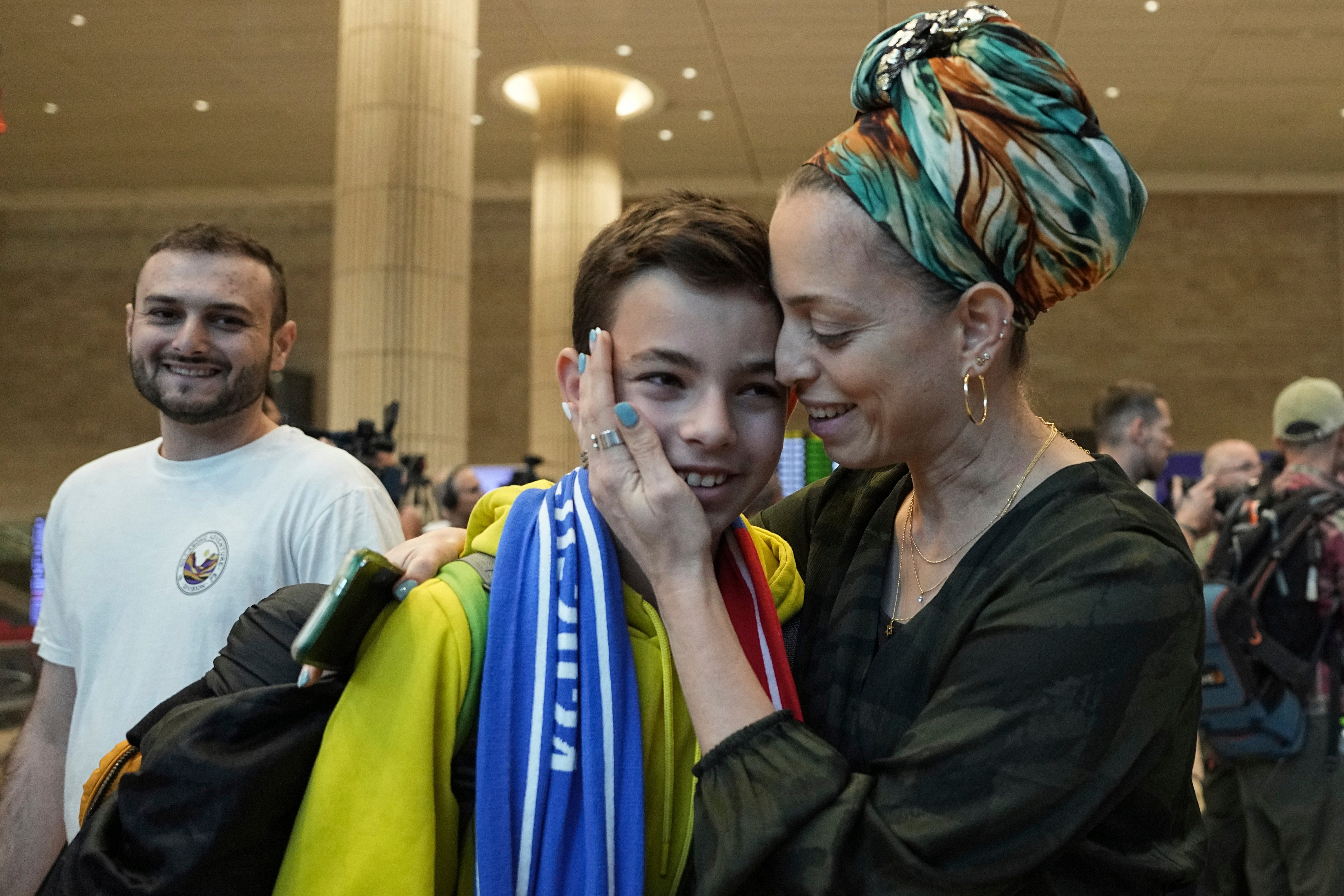 A woman embraces her son, who is a fan of Maccabi Tel Aviv, as he arrives at Israel's Ben-Gurion International Airport