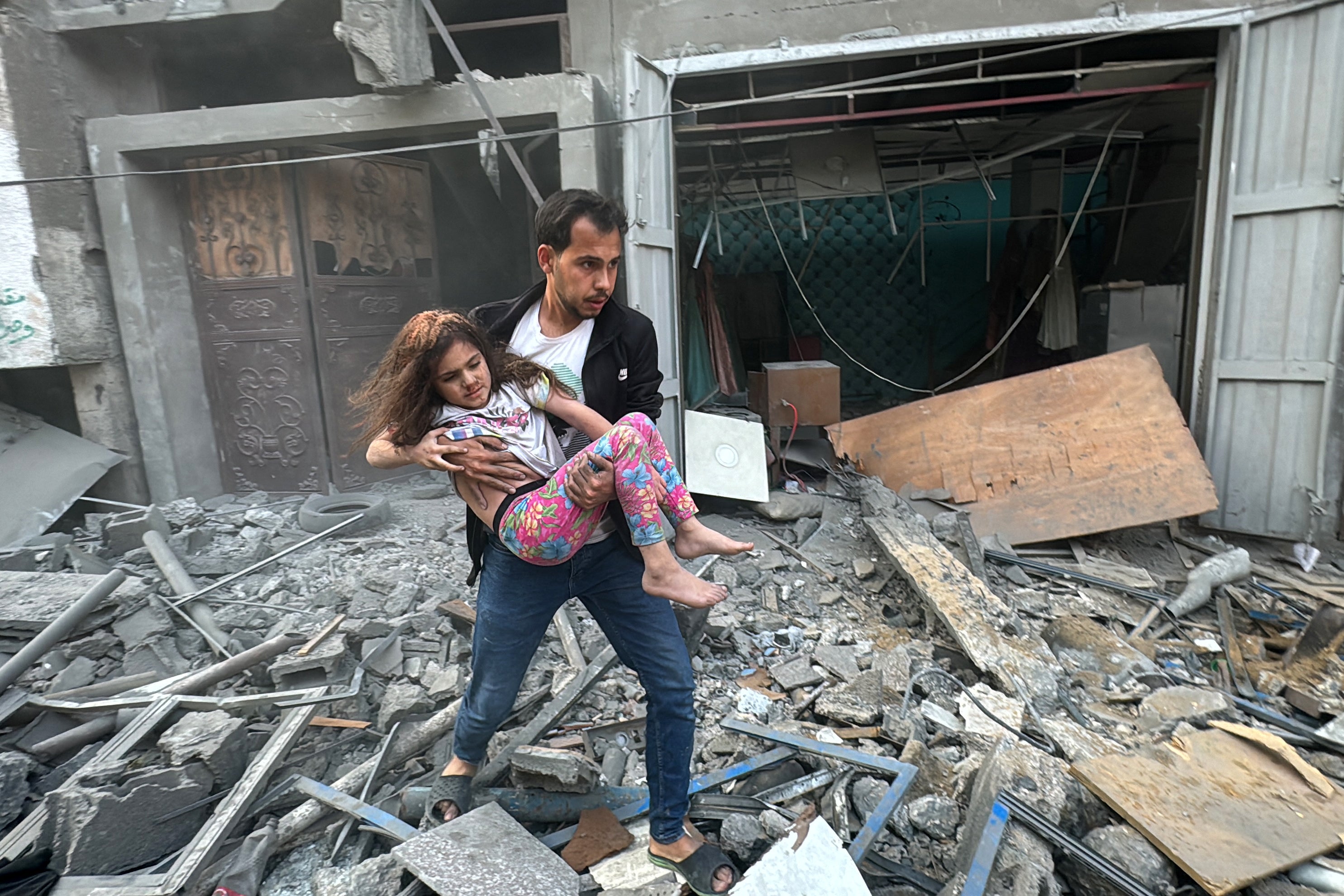 A Palestinian man carries an injured child from a home that was hit in an Israeli strike on the Jabalia refugee camp