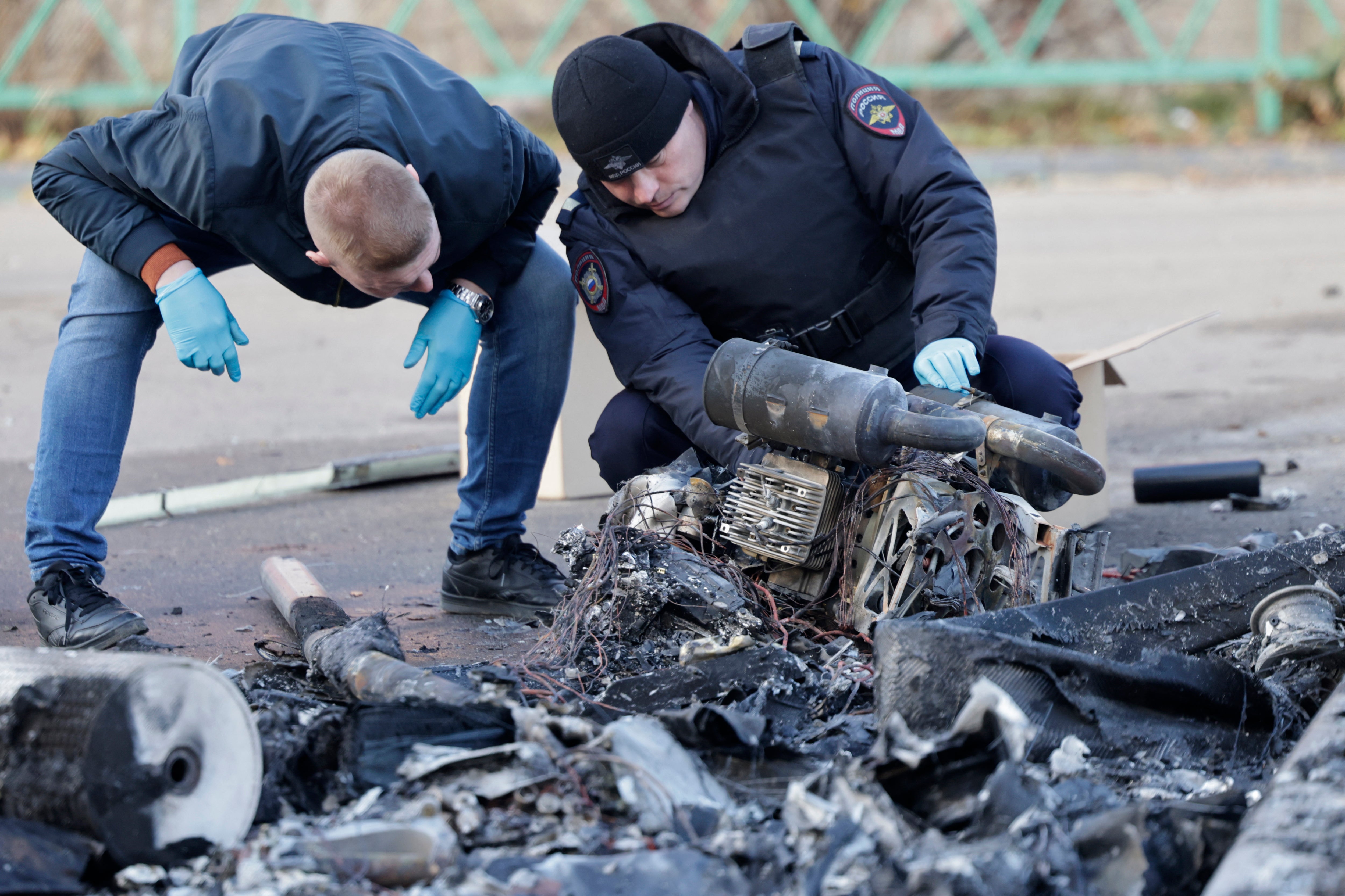 Russian law enforcement officers inspect the wreckage of a drone following a drone attack in the village of Sofyino, Moscow region