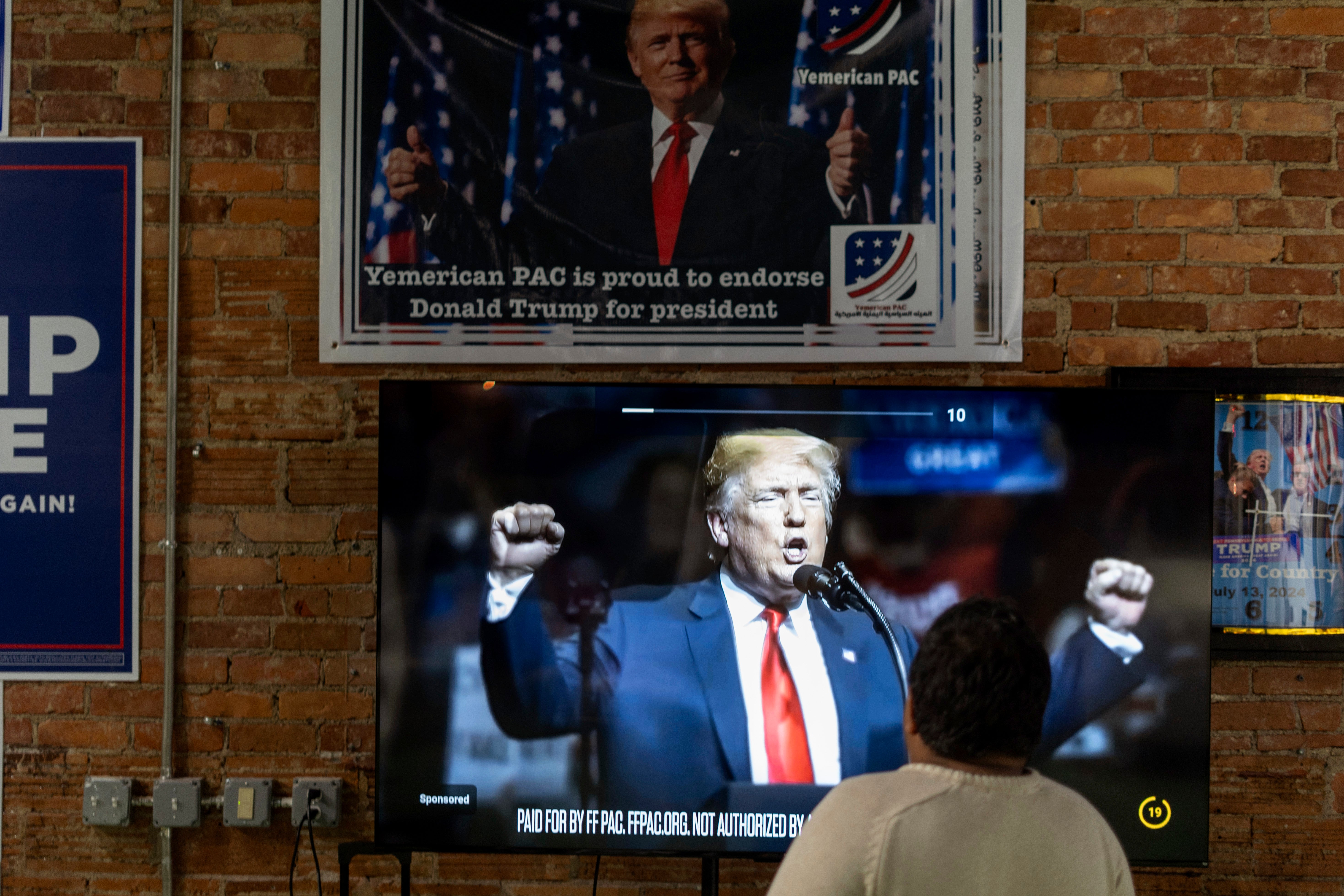 Arif Armanjisan watches an advertisement for Republican presidential nominee former President Donald Trump at his campaign office the night before the general election Monday, Nov. 4, 2024, in Hamtramck, Mich.