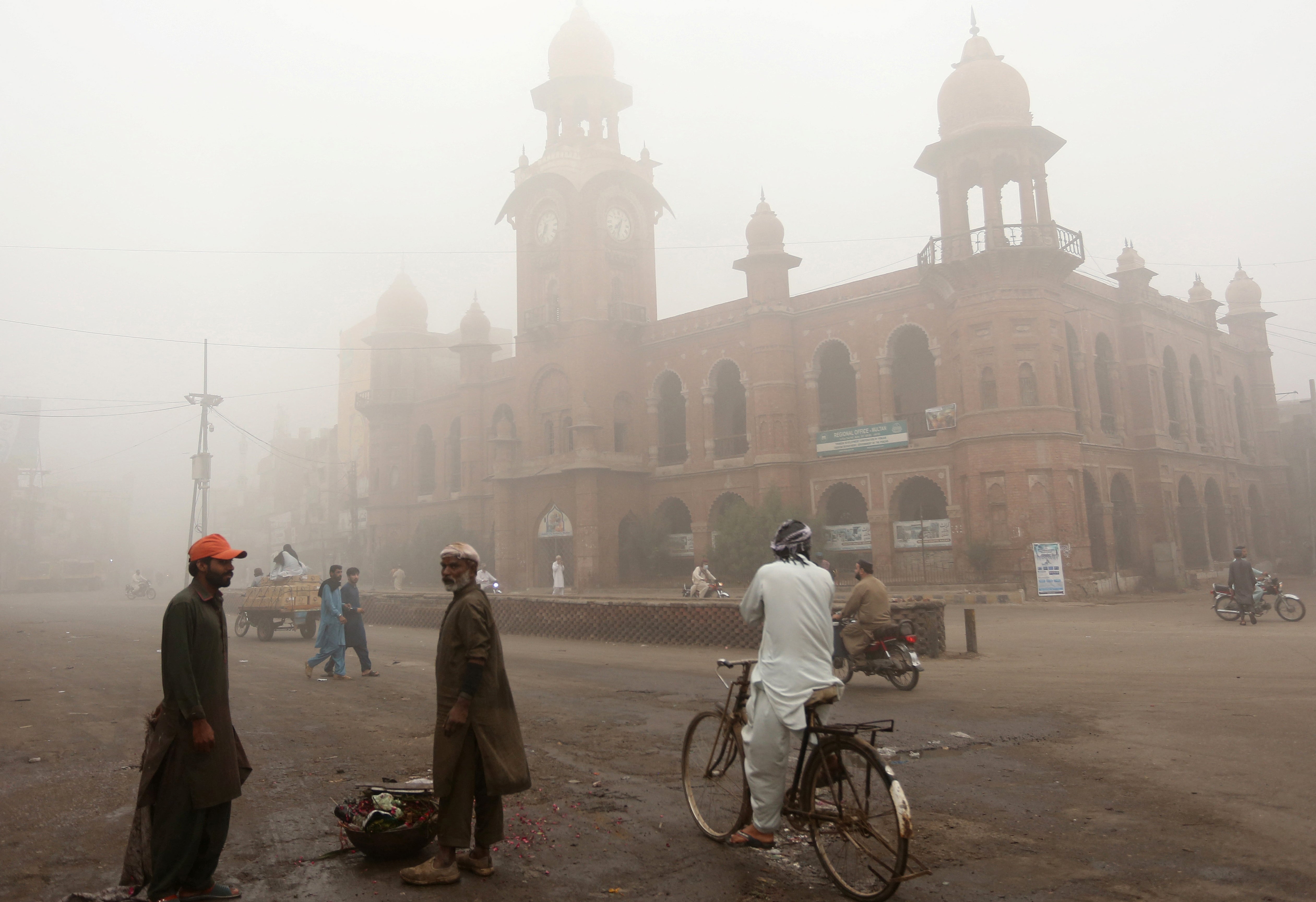 Commuters move along a street amid heavy smoggy conditions in Multan, Punjab