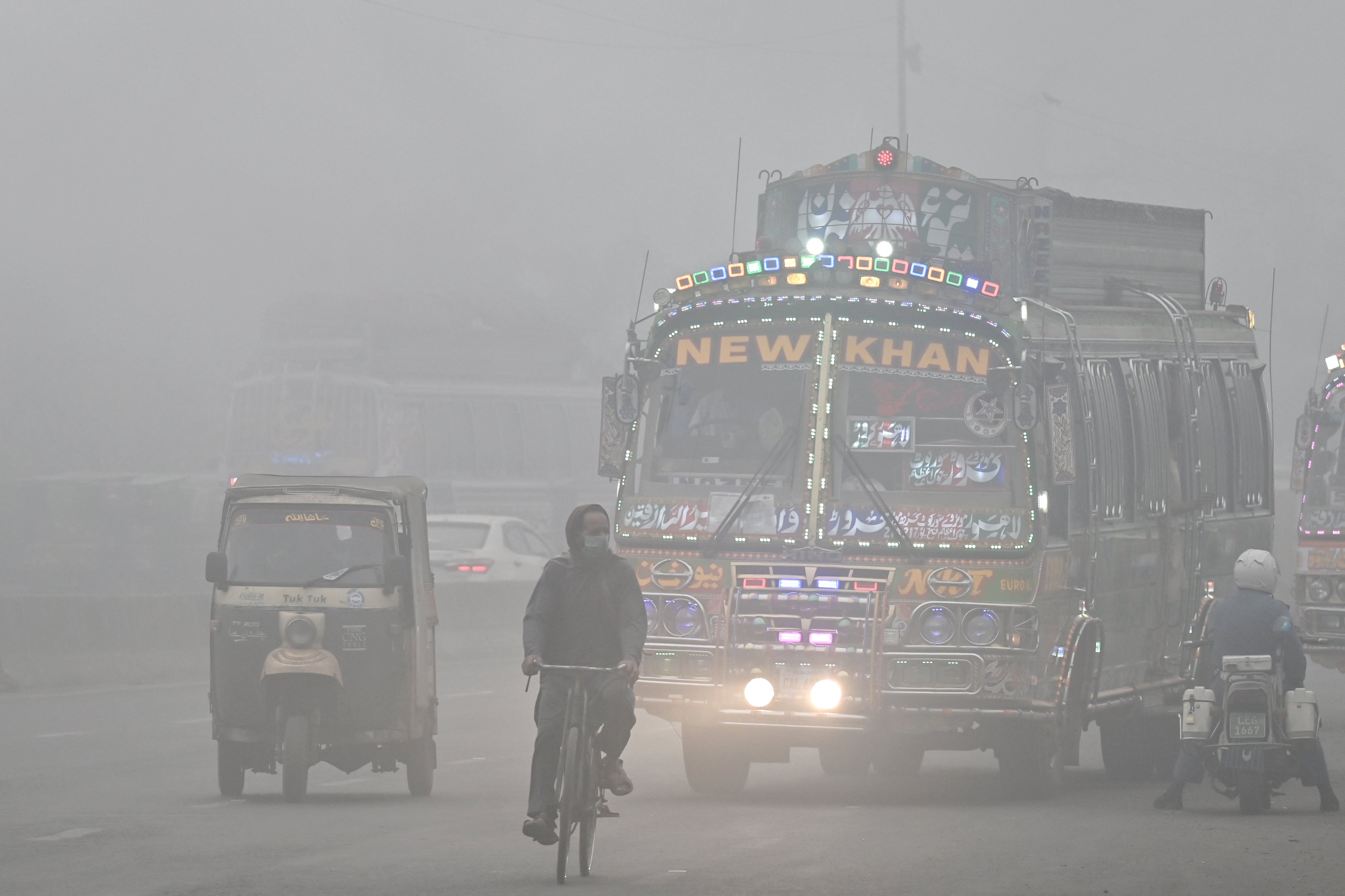 Commuters ride along a road engulfed in thick smog in Lahore